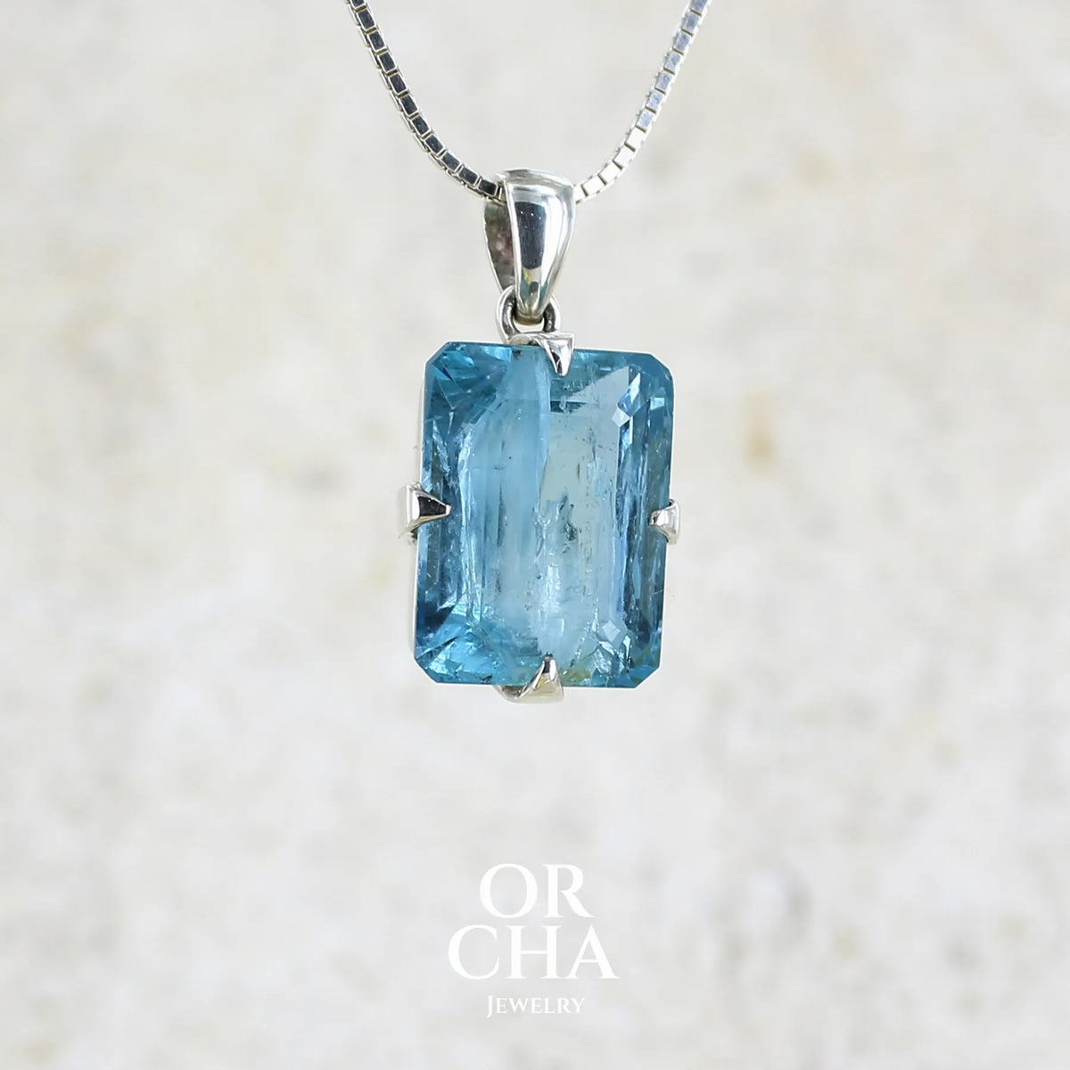 pendentif unisexe en argent massif sertie d'une aigue marine taillée de 17 carats de couleur bleu foncé profond et intense, pierre transparente avec de grosses inclusions. Pierre naturelle facettée de forme rectangulaire. Bijoux unique réalisée par Orchajewelry