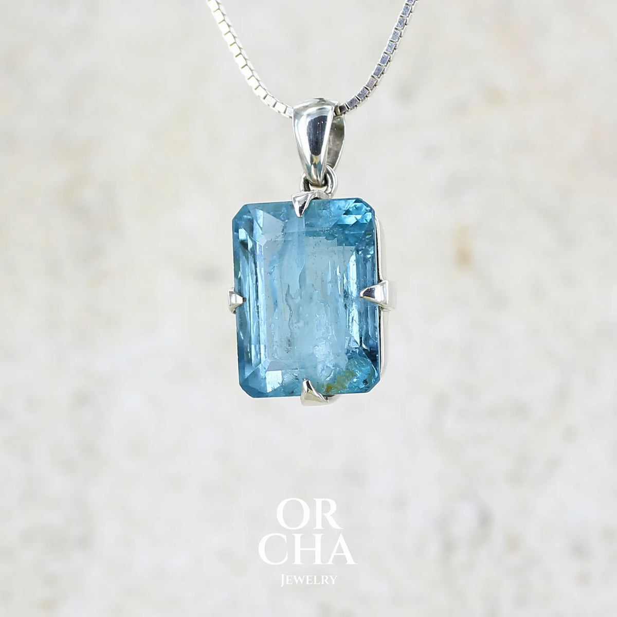 Pendentif unisexe en argent massif sertie d'une aigue marine taillée de 17 carats de couleur bleu foncé profond et intense, pierre transparente avec de grosses inclusions. Pierre naturelle facettée de forme rectangulaire. Bijoux unique réalisée par Orchajewelry