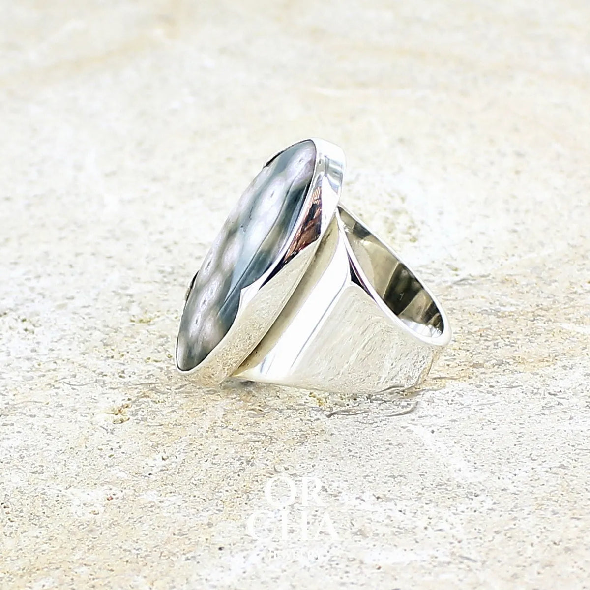 Profil d'une bague pour femme en argent massif sertie d'un cabochon ovale de jaspe orbiculaire de couleur vert kaki, blanc et rosé. Pierre de qualité opaque. Bijou unique réalisée en taille 58 par Orchajewelry