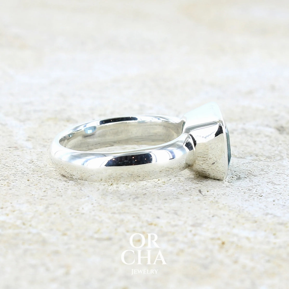 detail de l'anneau d'une bague pour femme en argent massif sertie d'une aigue marine taillée de 4 carats de couleur bleue foncé profonde  intense et lumineuse, pierre transparente avec inclusions. Pierre naturelle facettée de forme rectangulaire. Bijoux unique réalisée en taille 56 par Orchajewelry 