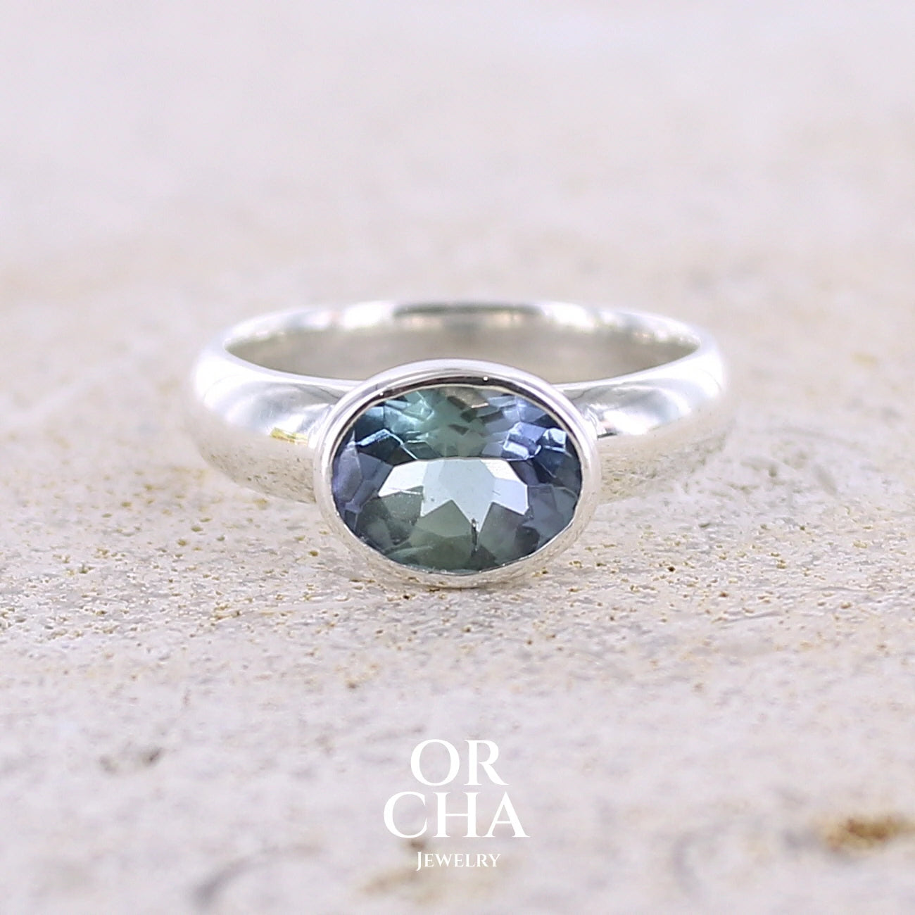 Bague solitaire pour femme en argent massif sertie d'une tanzanite bicolore. Pierre facettée de forme ovale de qualité transparente, propre à l'oeil. Pierre naturelle de couleur bleu verte et logés reflets violets. Bague réalisée en taille 50. Bijoux unique, éthique et durable présenté dans un coffret de notre marque, prêt à offrir. Livraison offerte, certificat d'authenticité, service client.

