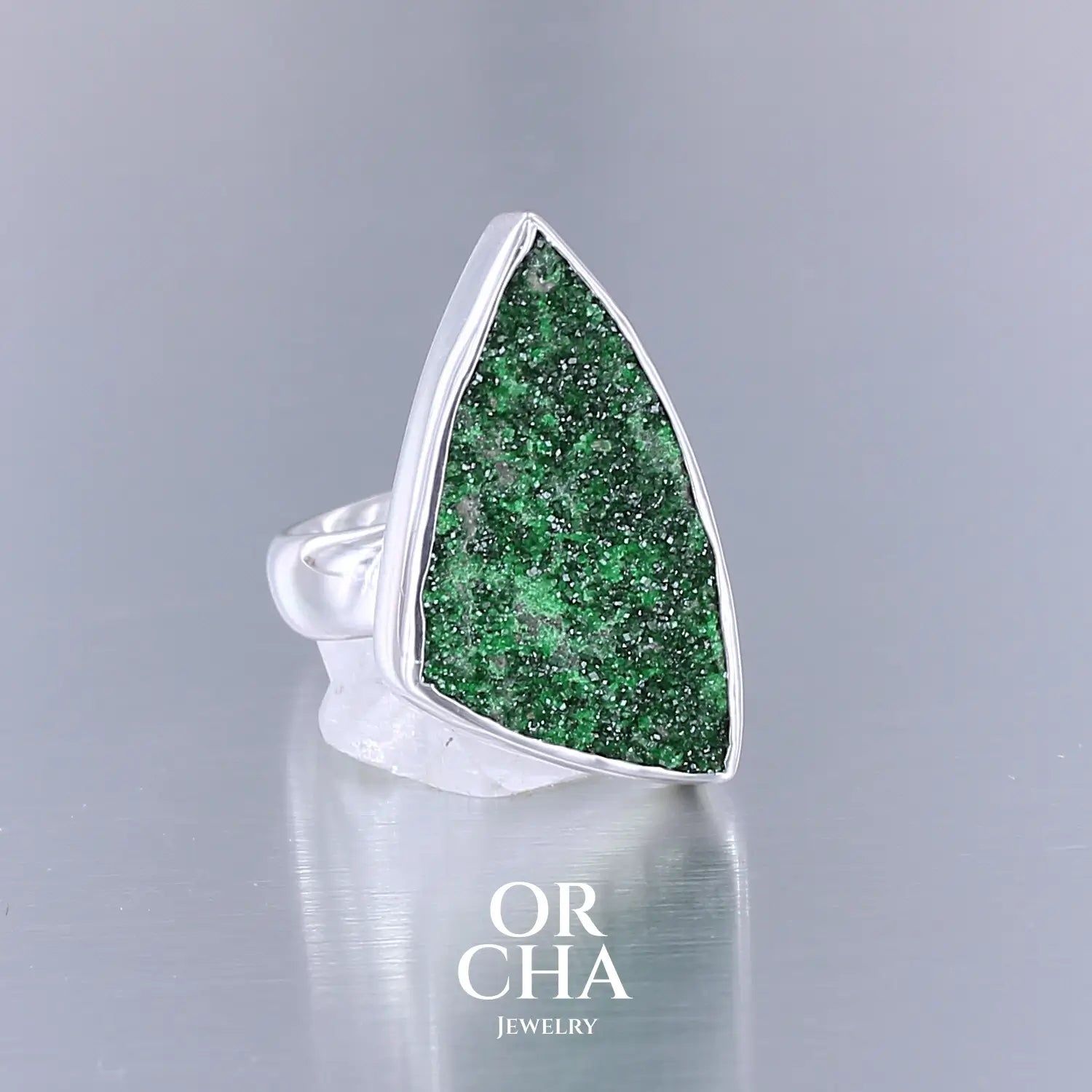 Bague en argent massif sertie d'un grenat Uvarovite brute. Pierre naturelle recouverte de cristaux scintillants de couleur verte. Bague réalisée en taille 58,5. Bijoux unique, éthique et durable présenté dans un coffret de notre marque, prêt à offrir. Livraison offerte, certificat d'authenticité, service client.