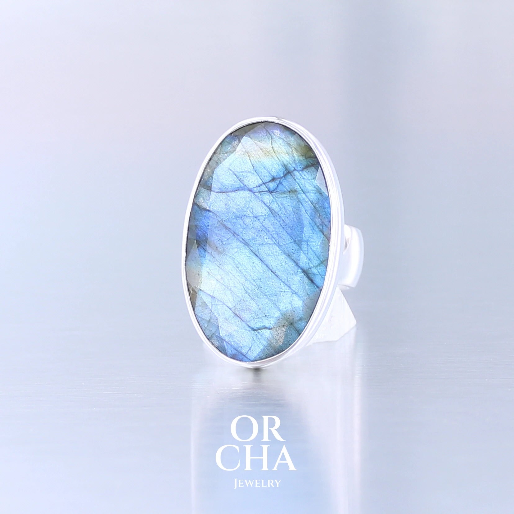 Bague unique pour femme en argent massif sertie d'une labradorite facettée aux reflets bleus et jaune selon la lumière. Pierre naturelle translucide présentant des inclusions fréquents sur ce type de pierre. Taille 54. Bijoux unique, éthique et durable présenté dans un coffret de notre marque, prêt à offrir. Livraison offerte, certificat d'authenticité, service client.