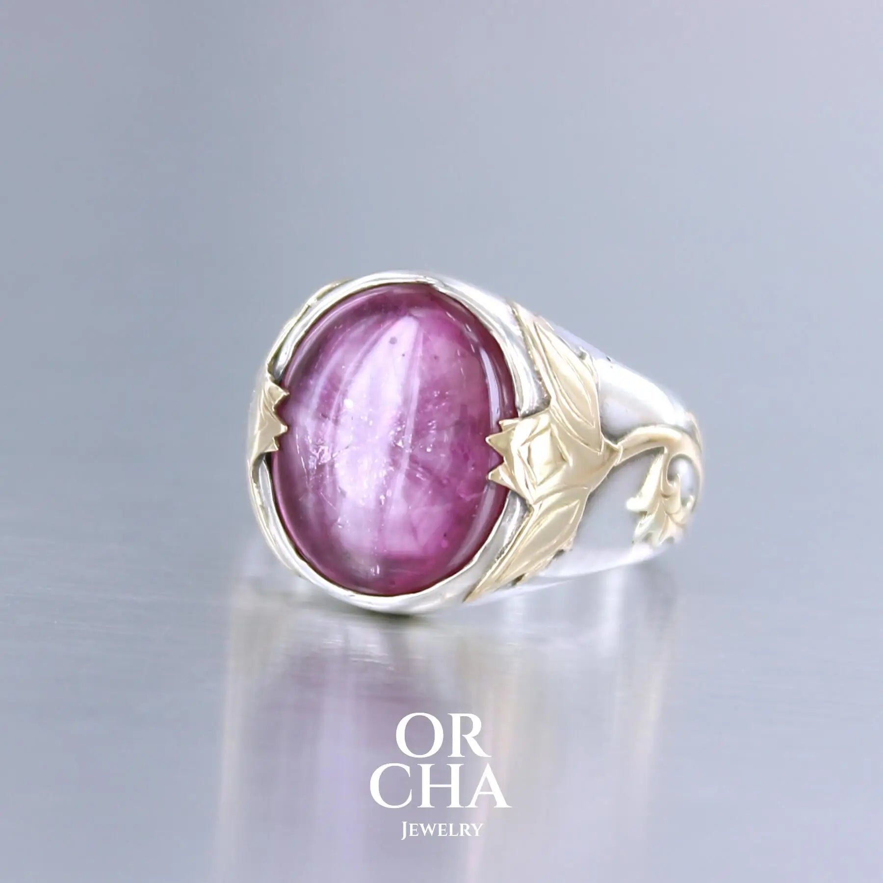 Bague chevalière pour femme en argent massif et or 18k où s'illustrent de chaque cotés de la bague des chardons. Cette bague est sertie d'un cabochon de rubis trapiche de couleur rouge rose. Pierre  translucide traitée au verre au plomb. Taille 60. Bijoux unique, éthique et durable présenté dans un coffret de notre marque, prêt à offrir. Livraison offerte, certificat d'authenticité, service client.