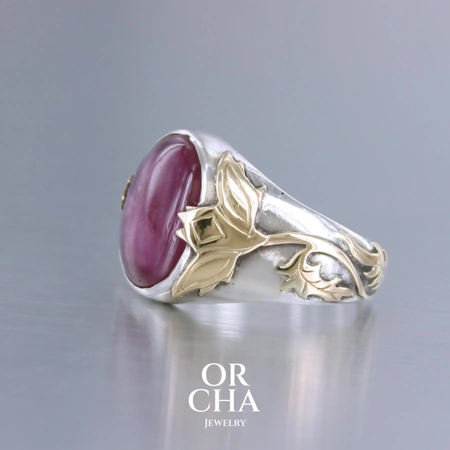 Bague chevalière pour femme en argent massif et or 18k où s'illustrent de chaque cotés de la bague des chardons. Cette bague est sertie d'un cabochon de rubis trapiche de couleur rouge rose. Pierre  translucide traitée au verre au plomb. Taille 60. Bijoux unique, éthique et durable présenté dans un coffret de notre marque, prêt à offrir. Livraison offerte, certificat d'authenticité, service client.