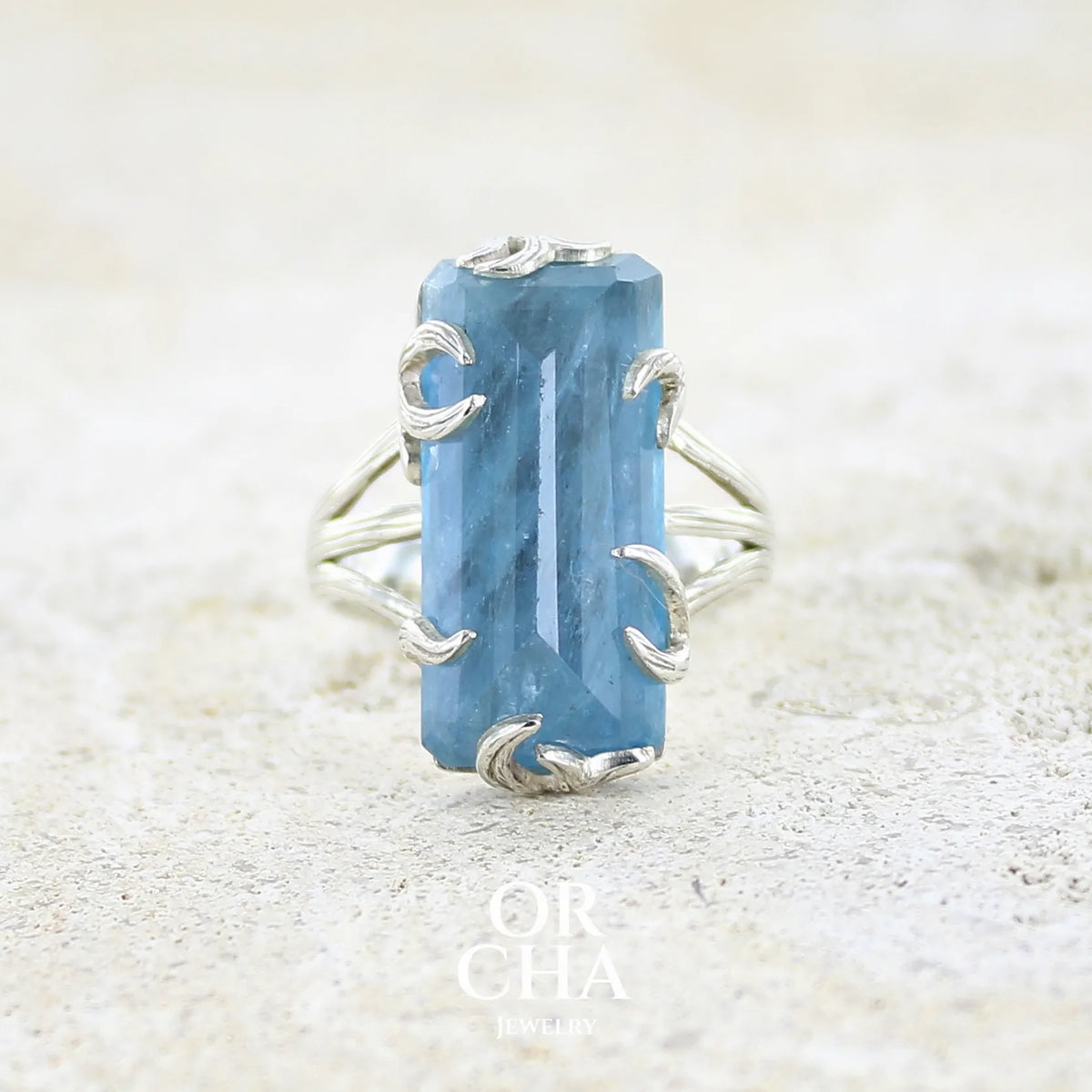 Bague pour femme en argent massif sertie d'une aigue-marine taillée de 15 carats de couleur bleue gris foncé, pierre transparente avec inclusions. Pierre naturelle facettée de forme rectangulaire. Bijoux unique réalisée en taille 59 par Orchajewelry