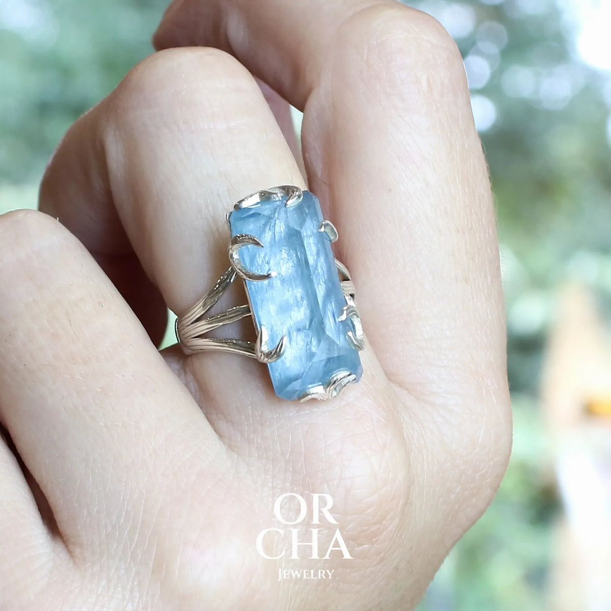 Bague pour femme en argent massif sertie d'une aigue-marine taillée de 15 carats de couleur bleue gris foncé, pierre transparente avec inclusions. Pierre naturelle facettée de forme rectangulaire. Bijoux unique réalisée en taille 59 par Orchajewelry