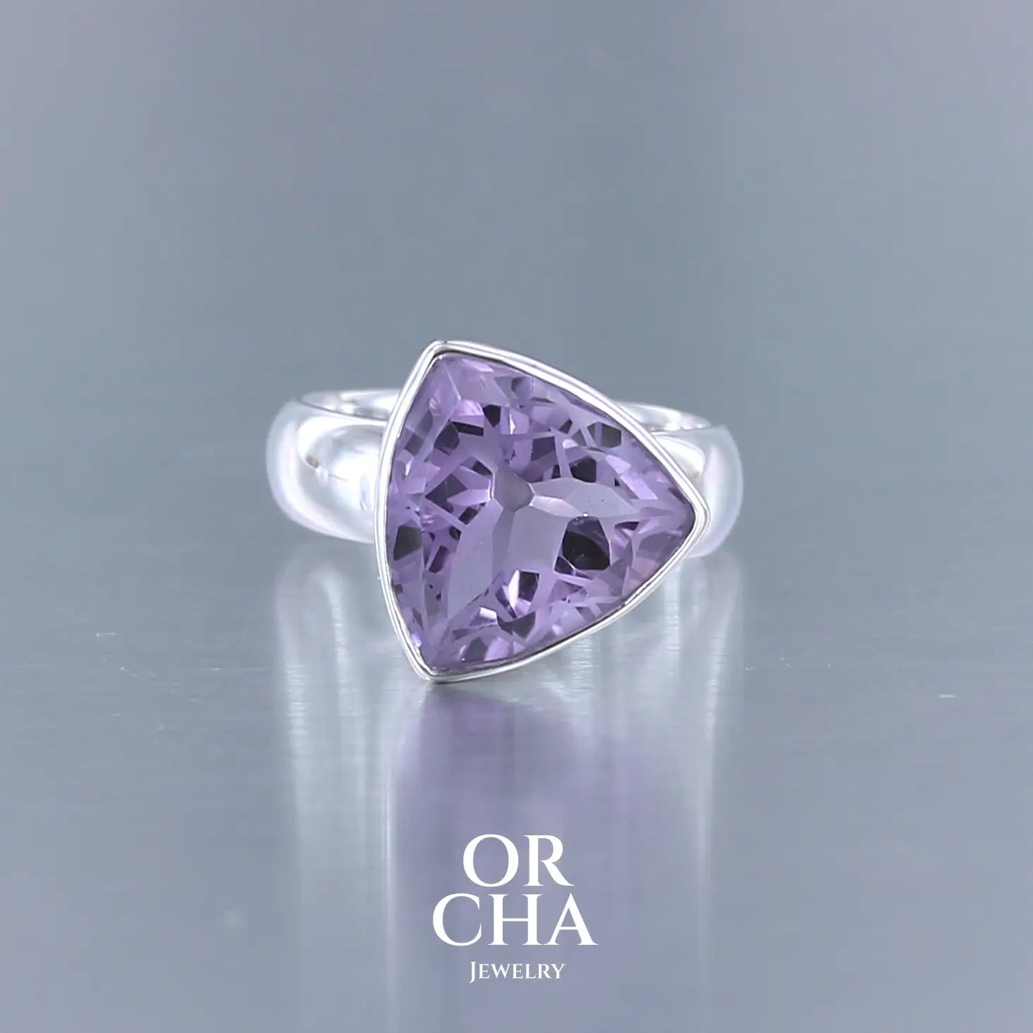Bague cocktail pour femme en argent massif sertie d'une Améthyste. Pierre taillée trillion de qualité transparente, propre à l'oeil. Pierre naturelle de couleur violette clair gravée de motifs géométriques de fleur de vie. Tailles 58. Bijoux unique, éthique et durable présenté dans un coffret de notre marque, prêt à offrir. Livraison offerte, certificat d'authenticité, service client.
