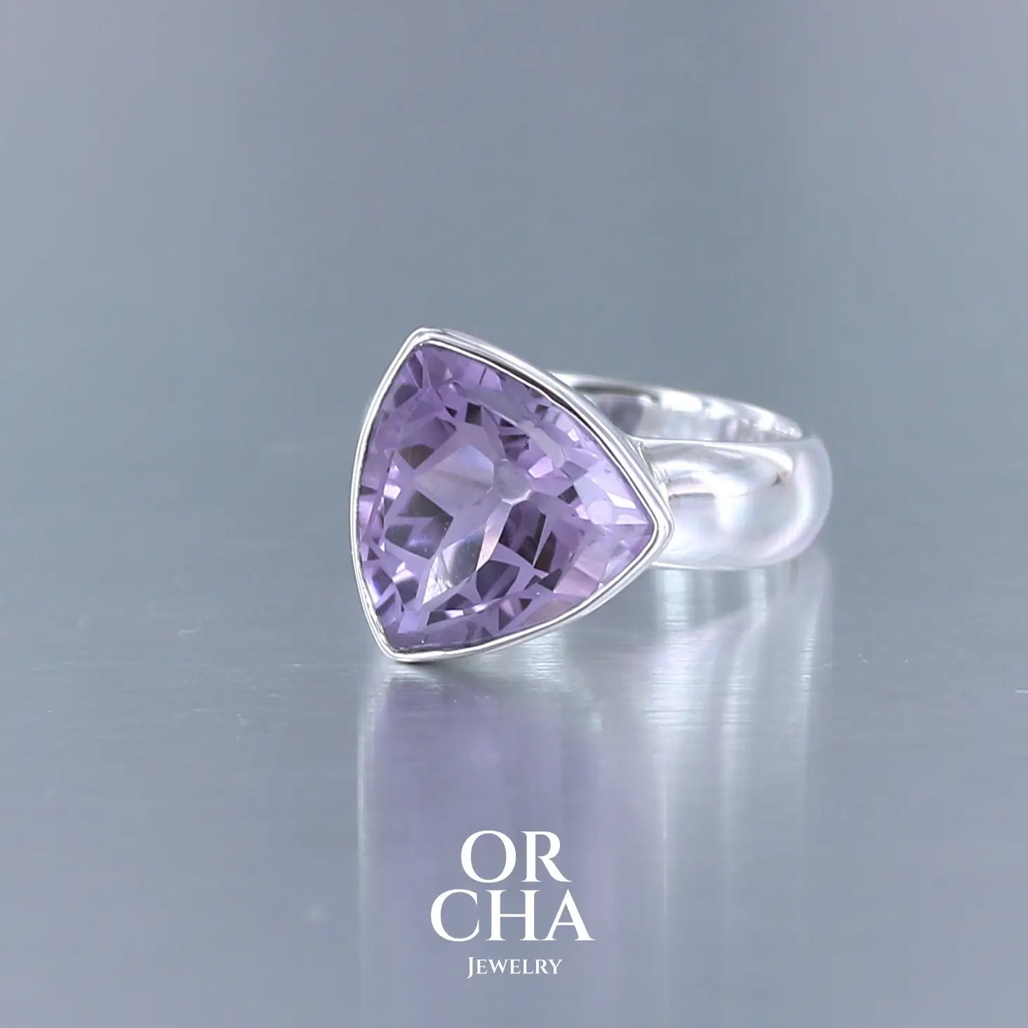 Bague cocktail pour femme en argent massif sertie d'une Améthyste. Pierre taillée trillion de qualité transparente, propre à l'oeil. Pierre naturelle de couleur violette clair gravée de motifs géométriques de fleur de vie. Tailles 58. Bijoux unique, éthique et durable présenté dans un coffret de notre marque, prêt à offrir. Livraison offerte, certificat d'authenticité, service client.