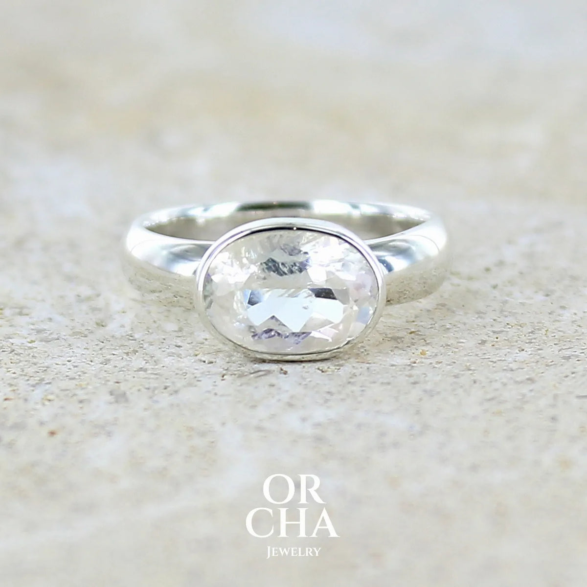 Bague cocktail pour femme en argent massif 925 sertie d'une pierre de lune de Madagascar taillée de 2,18 carats, pierre incolore aux reflets orangés et arc en ciel. Pierre transparente avec inclusions. Bijoux unique réalisé en taille 52 par Orcha Jewelry