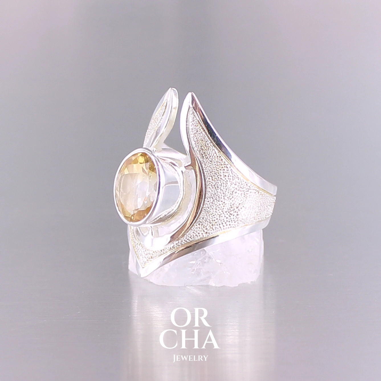 Grande bague contemporaine pour femme en argent massif sertie d'une Citrine. Pierre facettée de forme ovale de qualité transparente, propre à l'oeil. Pierre naturelle de couleur jaune doré lumineux. Bijoux unique, éthique et durable présenté dans un coffret de notre marque, prêt à offrir. Livraison offerte, certificat d'authenticité, service client.
