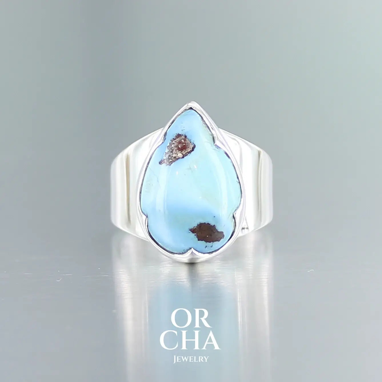 Bague de créateur en argent massif pour femme sertie d'une Turquoise Golden hill. Pierre cabochon en forme de goutte de qualité opaque. Pierre naturelle en camaïeu de bleu . Bague réalisée en taille 56. Bijoux unique, éthique et durable présenté dans un coffret de notre marque, prêt à offrir. Livraison offerte, certificat d'authenticité, service client.