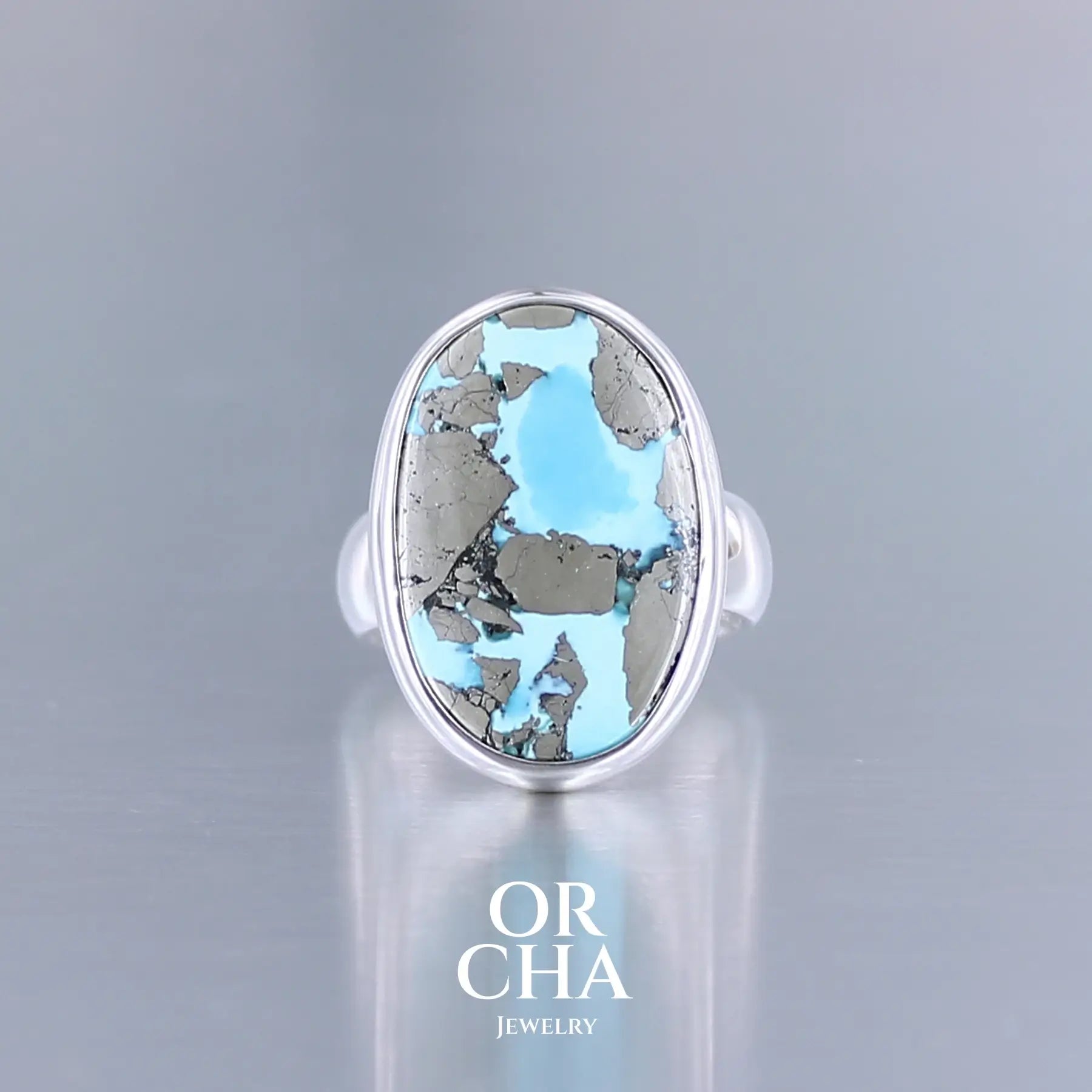 Bague pour femme en argent massif sertie d'une Turquoise perse à inclusions de Pyrite. Cabochon de forme ovale, pierre de couleur bleu ciel intense à inclusions dorées de pyrite. Qualité opaque. Comme l'immense majorité des Turquoises cette pierre a été stabilisée par traitement. Taille 53. Bijoux unique, éthique et durable présenté dans un coffret de notre marque, prêt à offrir. Livraison offerte, certificat d'authenticité, service client.