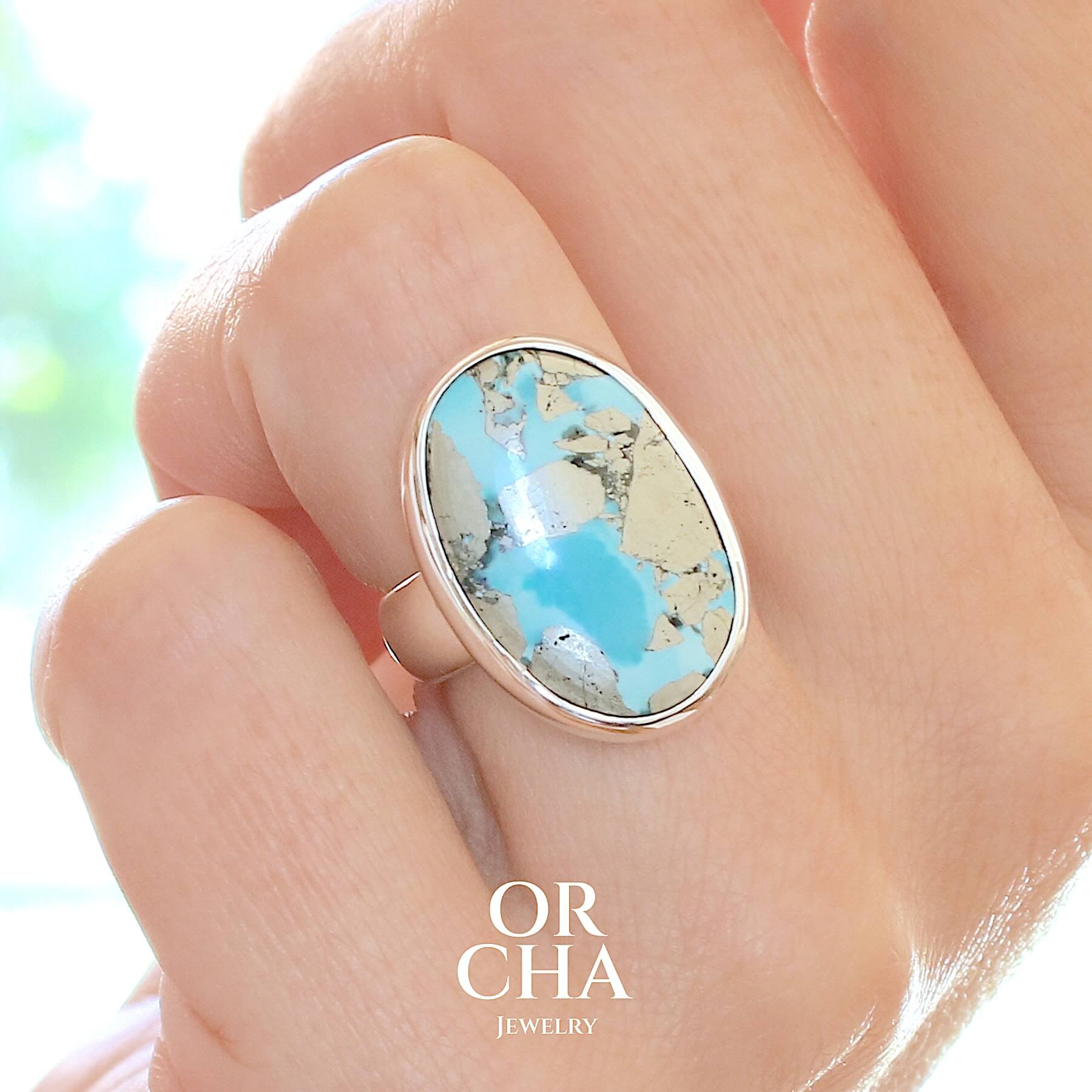 Bague pour femme en argent massif sertie d'une Turquoise perse à inclusions de Pyrite. Cabochon de forme ovale, pierre de couleur bleu ciel intense à inclusions dorées de pyrite. Qualité opaque. Comme l'immense majorité des Turquoises cette pierre a été stabilisée par traitement. Taille 53. Bijoux unique, éthique et durable présenté dans un coffret de notre marque, prêt à offrir. Livraison offerte, certificat d'authenticité, service client.