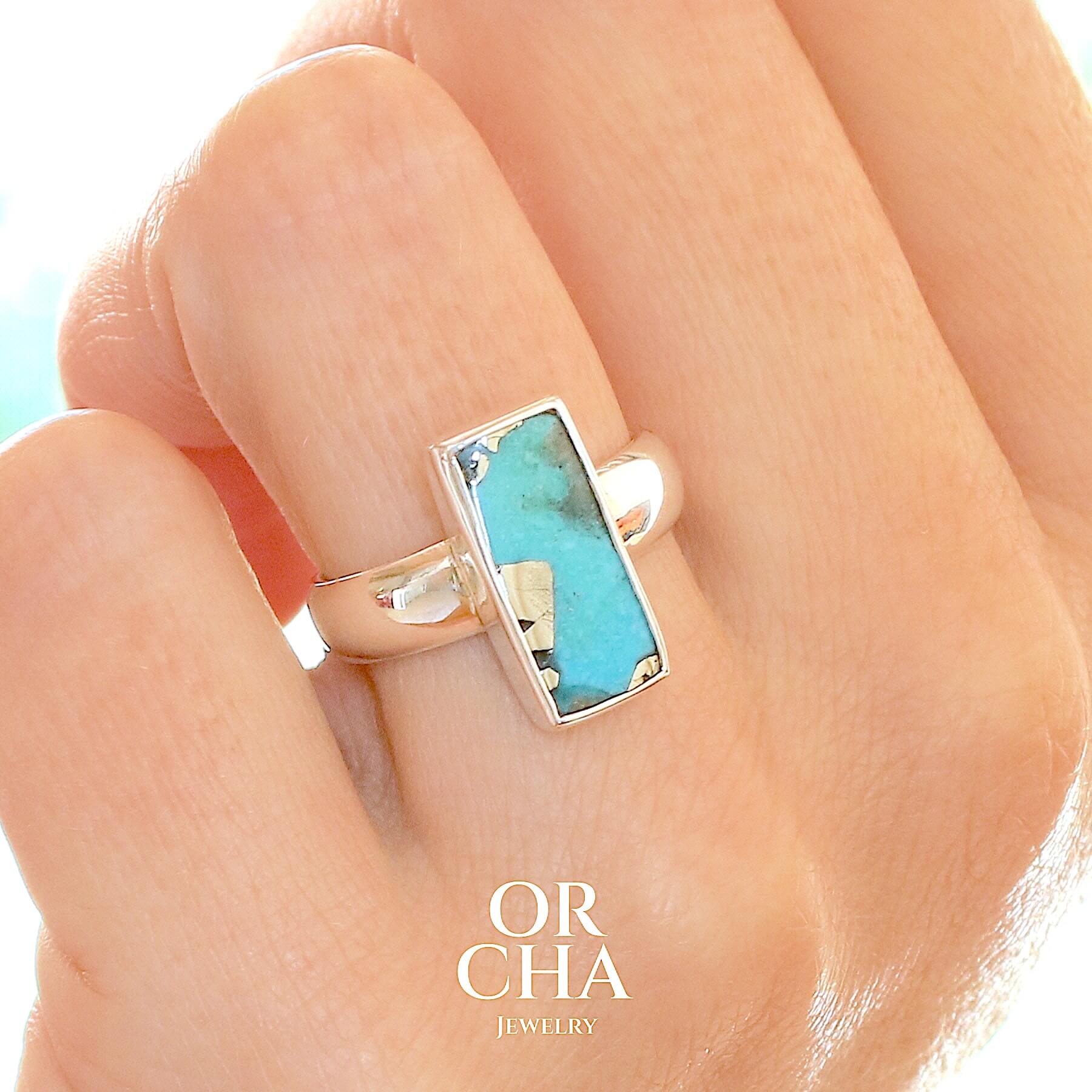 Bague pour femme en argent massif sertie d'une Turquoise perse à inclusions de Pyrite. Tranche polie de turquoise de forme rectangulaire. Pierre de couleur bleu ciel intense à inclusions dorées de pyrite. Qualité opaque. Comme l'immense majorité des Turquoises cette pierre a été stabilisée par traitement. Taille 56. Bijoux unique, éthique et durable présenté dans un coffret de notre marque, prêt à offrir. Livraison offerte, certificat d'authenticité, service client.