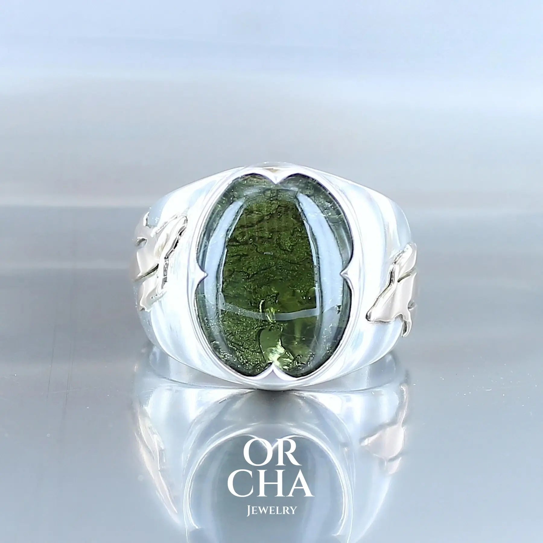 Bague pour homme en argent massif et or 9k où s'illustrent de chaque cotés de la bague des carpes Koï en or. Cette bague est sertie d'un cabochon de moldavite de couleur vert foncé. Pierre  naturelle transparente qui laisse voir le fond de la pierre laissé brute. Taille 66. Bijoux unique, éthique et durable présenté dans un coffret de notre marque, prêt à offrir. Livraison offerte, certificat d'authenticité, service client.