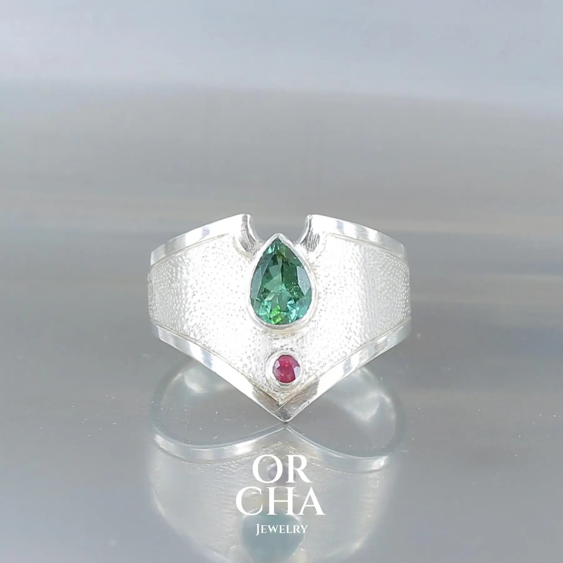 Bague pour femme en argent massif sertie d'une tourmaline verte ainsi que d'une petite tourmaline rouge rose. Pierre naturelle facettée taillée en forme goutte. Pierre transparente, propre à l'oeil. Taille 59. Bijoux unique, éthique et durable présenté dans un coffret de notre marque, prêt à offrir. Livraison offerte, certificat d'authenticité, service client.