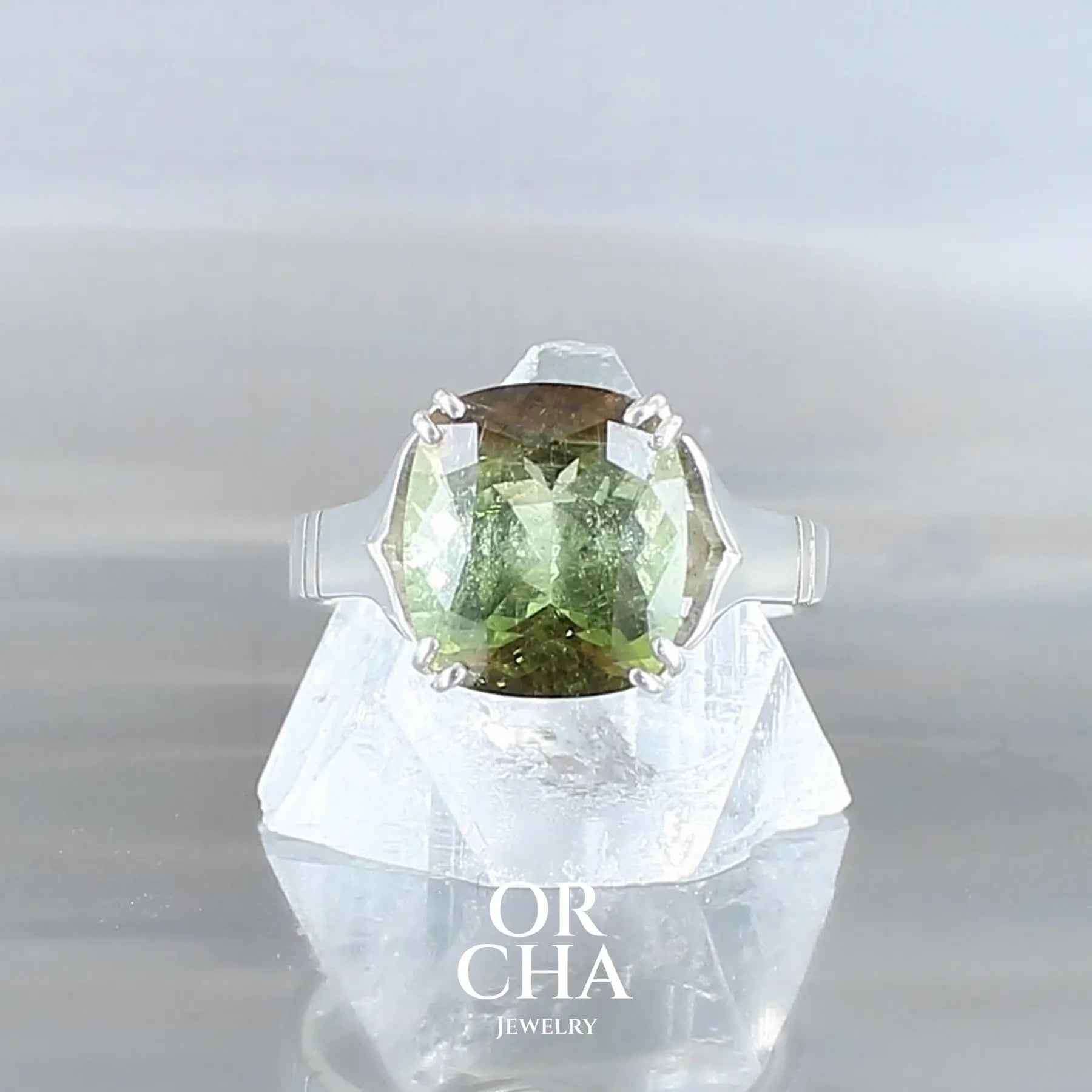 Superbe Bague solitaire pour femme en argent massif sertie d'une Tourmaline bicolore a dominance verte et bronze sur les bords de la pierre. Pierre naturelle facettée en coussin de 4,5 carats de qualité transparente présentant des inclusions. Taille 54. Bijoux unique, éthique et durable présenté dans un coffret de notre marque, prêt à offrir. Livraison offerte, certificat d'authenticité, service client.