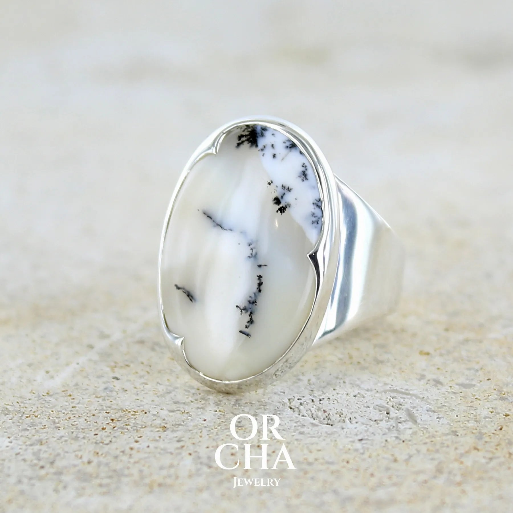 Bague pour femme en argent massif sertie d'un cabochon ovale d'agate dendritique de couleur blanc pur et noir. Pierre opaque translucide à inclusions paysages de dendrites de manganèse noires contrastées. Bijou unique réalisé en taille 54 par Orchajewelry