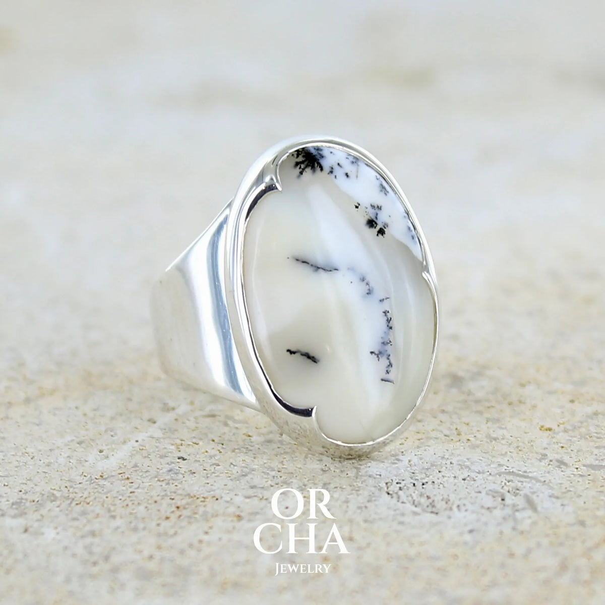 Bague pour femme en argent massif sertie d'un cabochon ovale d'agate dendritique de couleur blanc pur et noir. Pierre opaque translucide à inclusions paysages de dendrites de manganèse noires contrastées. Bijou unique réalisé en taille 54 par Orchajewelry