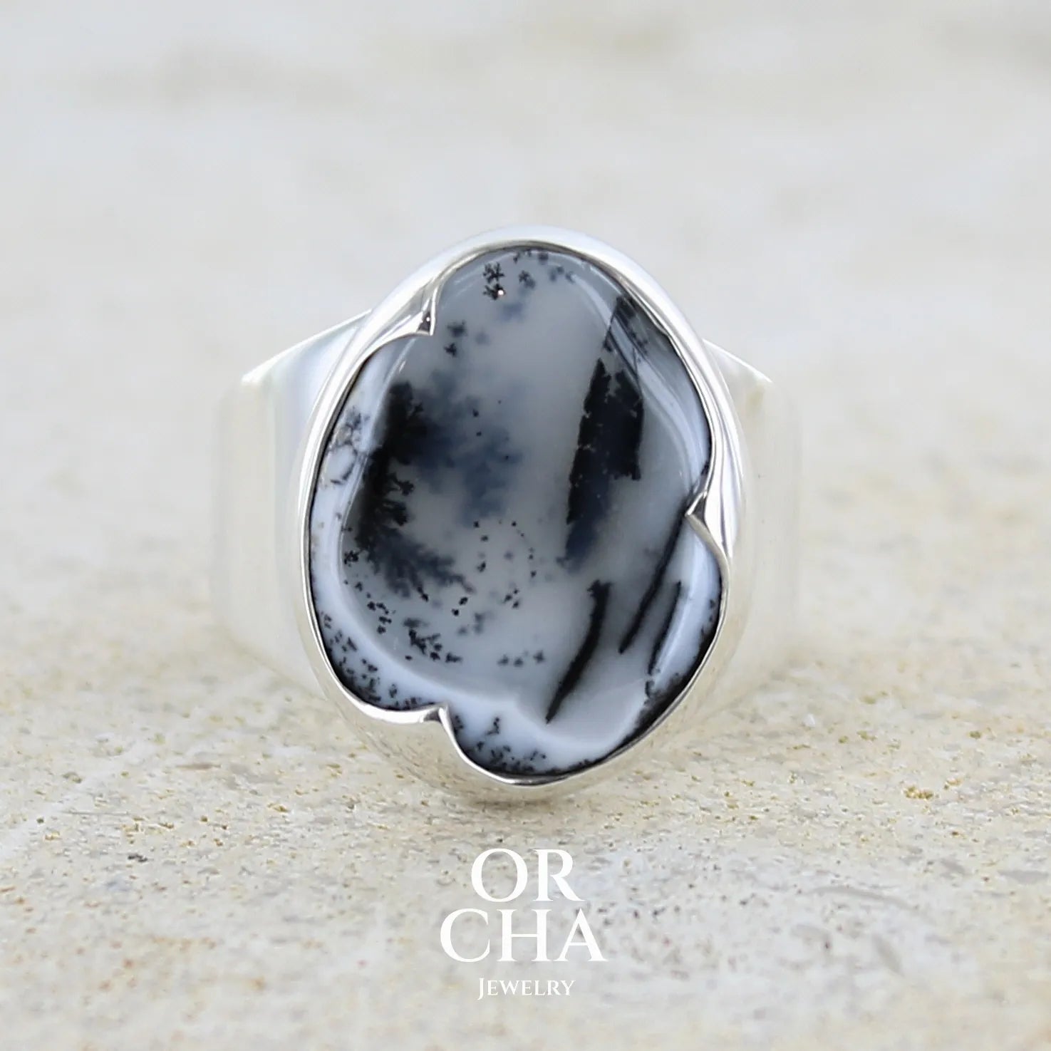 Bague pour femme en argent massif sertie d'un cabochon ovale d'agate dendritique de couleur blanc pur et noir. Pierre opaque translucide à inclusions paysages de dendrites de manganèse noires contrastées. Bijou unique réalisée en taille 54 par Orchajewelry