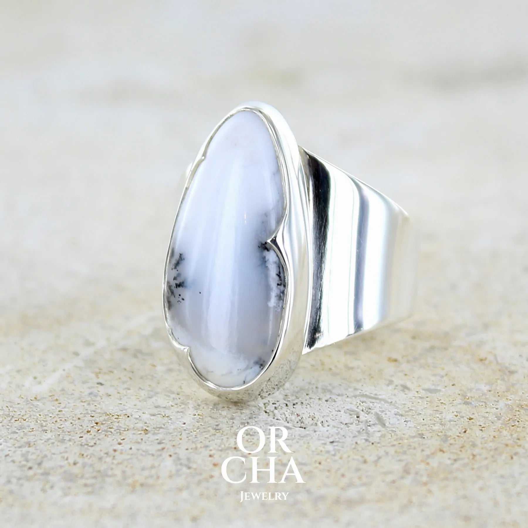 Bague pour femme en argent massif sertie d'un cabochon ovale d'agate dendritique de couleur blanc pur et noir. Pierre opaque translucide à inclusions paysages de dendrites de manganèse noires contrastées. Bijou unique réalisée en taille 60 par Orchajewelry