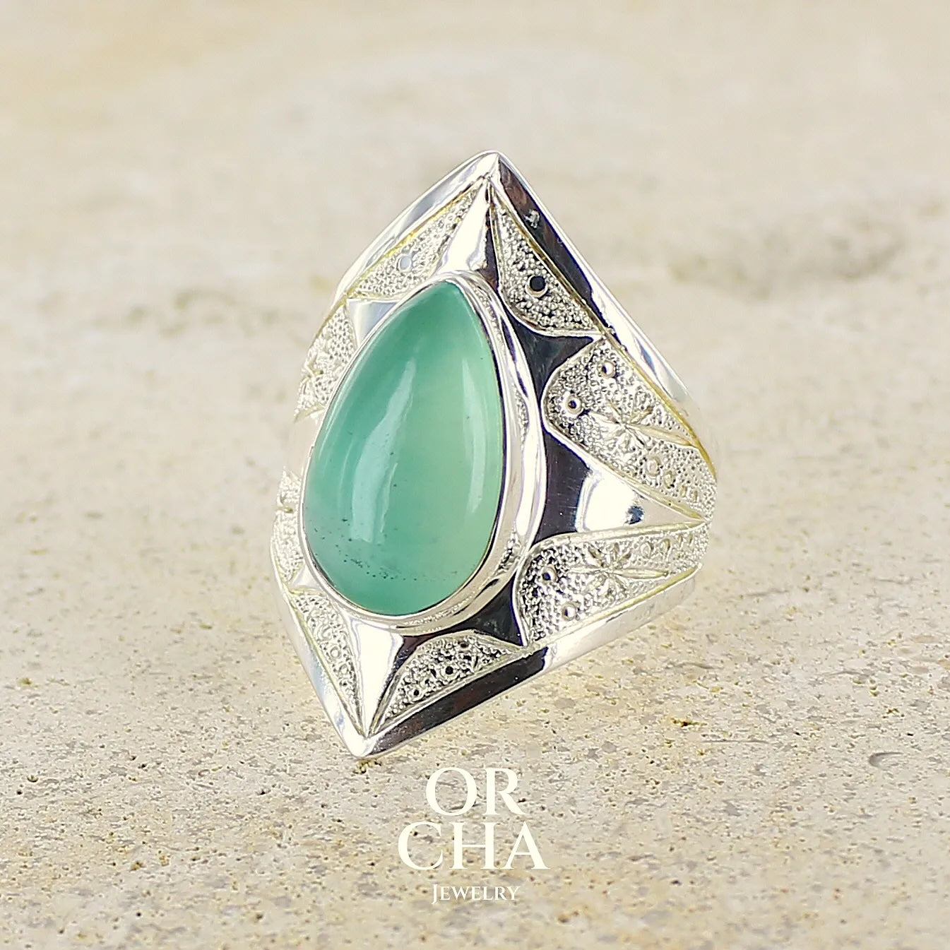 Bague étoile pour femme en argent massif, sertie d'un cabochon de calcédoine bleue verte. Pierre taillée de en forme de goutte. Pierre translucide. bijou unique réalisée en taille 59 par Orcha Jewelry  