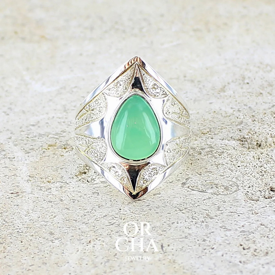Bague étoile pour femme en argent massif sculptées d'étoiles et autres corps célestes sertie d'un cabochon de chrysoprase de couleur verte pastel. Pierre naturelle de qualité translucide taillée goutte. Bague unique réalisée en taille 57 par Orcha jewelry