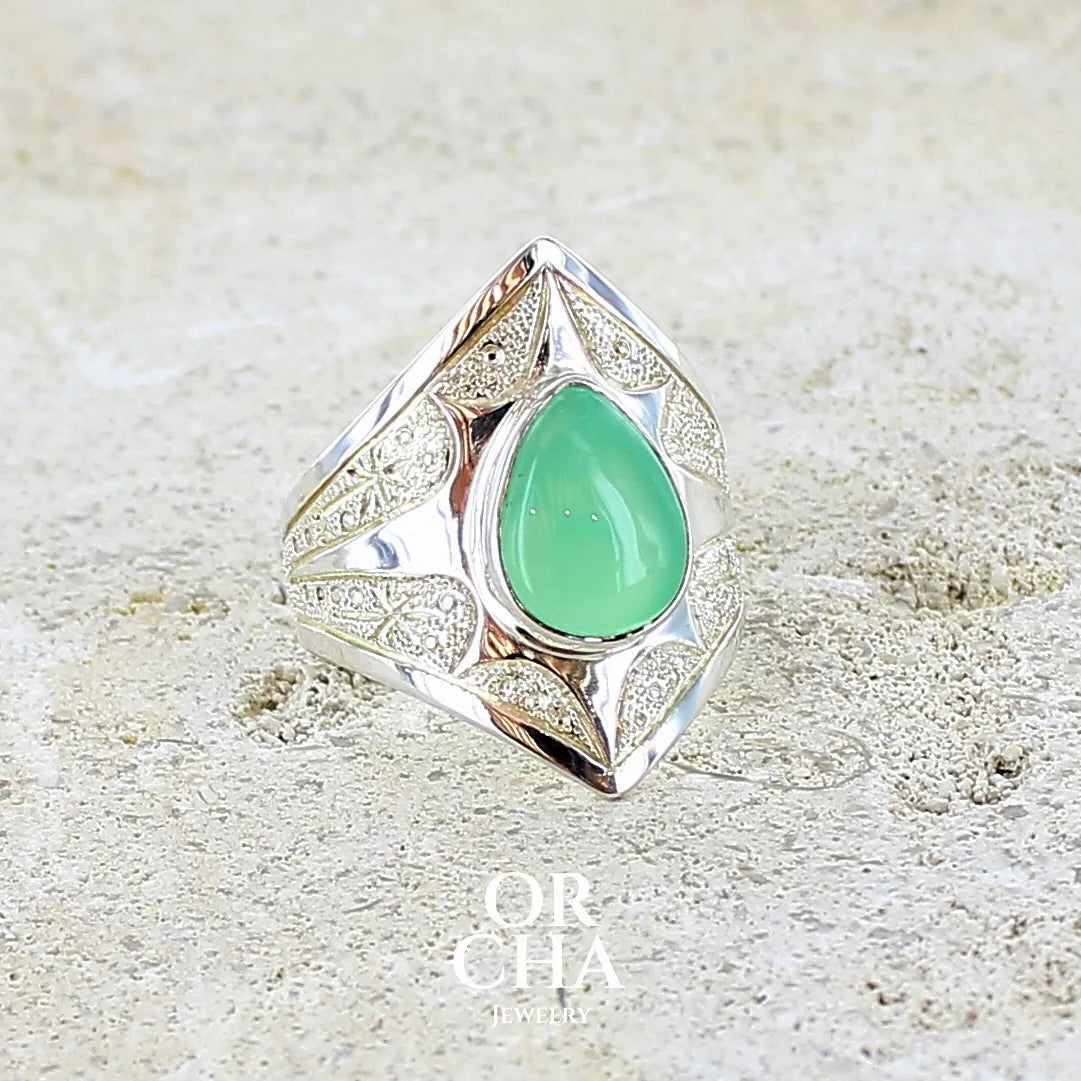 Bague étoile pour femme en argent massif sculptées d'étoiles et autres corps célestes sertie d'un cabochon de chrysoprase de couleur verte pastel. Pierre naturelle de qualité translucide taillée goutte. Bague unique réalisée en taille 57 par Orcha jewelry