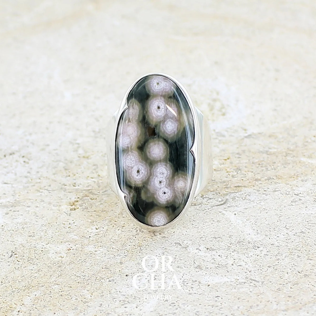 Bague pour femme en argent massif sertie d'un cabochon ovale de jaspe orbiculaire de couleur vert kaki, blanc et rosé. Pierre de qualité opaque. Bijou unique réalisée en taille 58 par Orchajewelry
