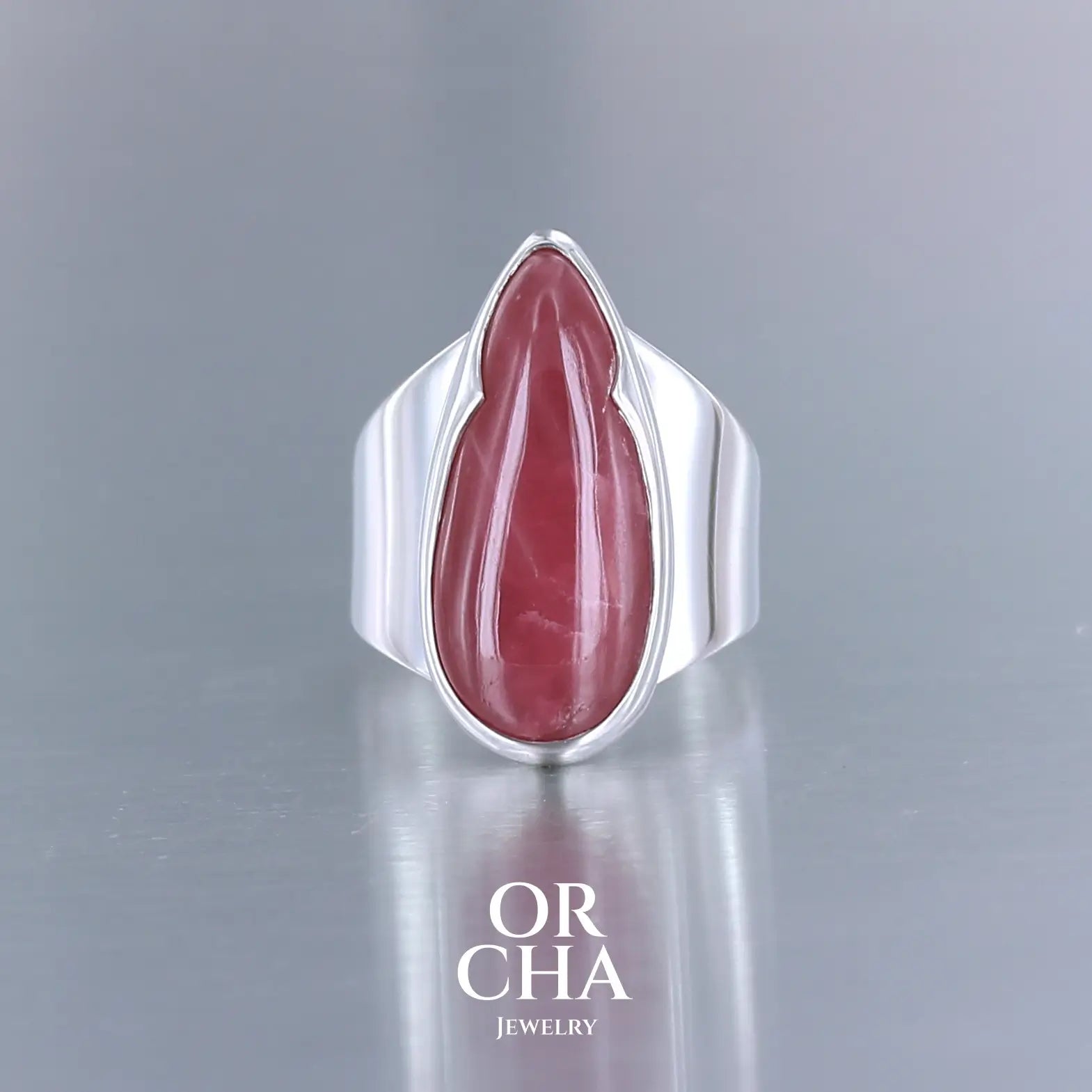 Grande bague pour femme en argent massif sertie d'une Rhodonite. Pierre cabochon en forme de goutte, pierre naturelle de qualité rare de couleur rouge coquelicot. Pierre fine de qualité opaque. Taille 56. Bijoux unique, éthique et durable présenté dans un coffret de notre marque, prêt à offrir. Livraison offerte, certificat d'authenticité, service client.
