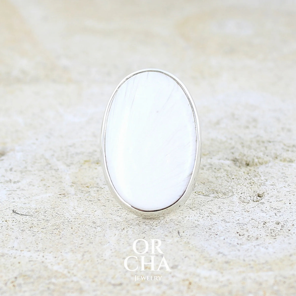 Bague pour femme en argent massif sertie d'un cabochon de scolecite de couleur blanc pur. Pierre naturelle de qualité opaque taillée en ovale. Bague unique réalisée en taille 58 par Orcha jewelry