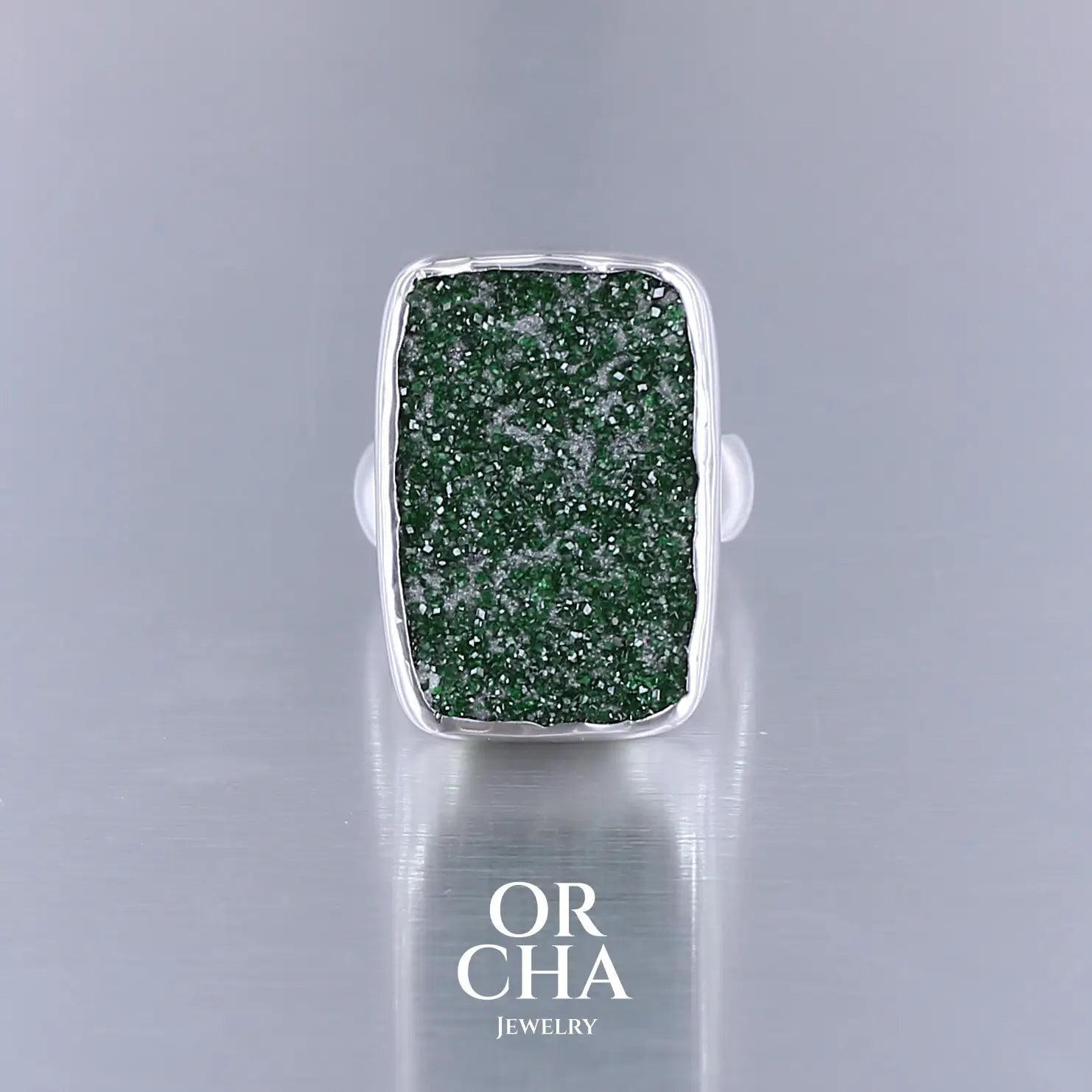 Bague en argent massif sertie d'un grenat Uvarovite brute. Pierre naturelle recouverte de cristaux scintillants de couleur verte. Bague réalisée en taille 55. Bijoux unique, éthique et durable présenté dans un coffret de notre marque, prêt à offrir. Livraison offerte, certificat d'authenticité, service client.