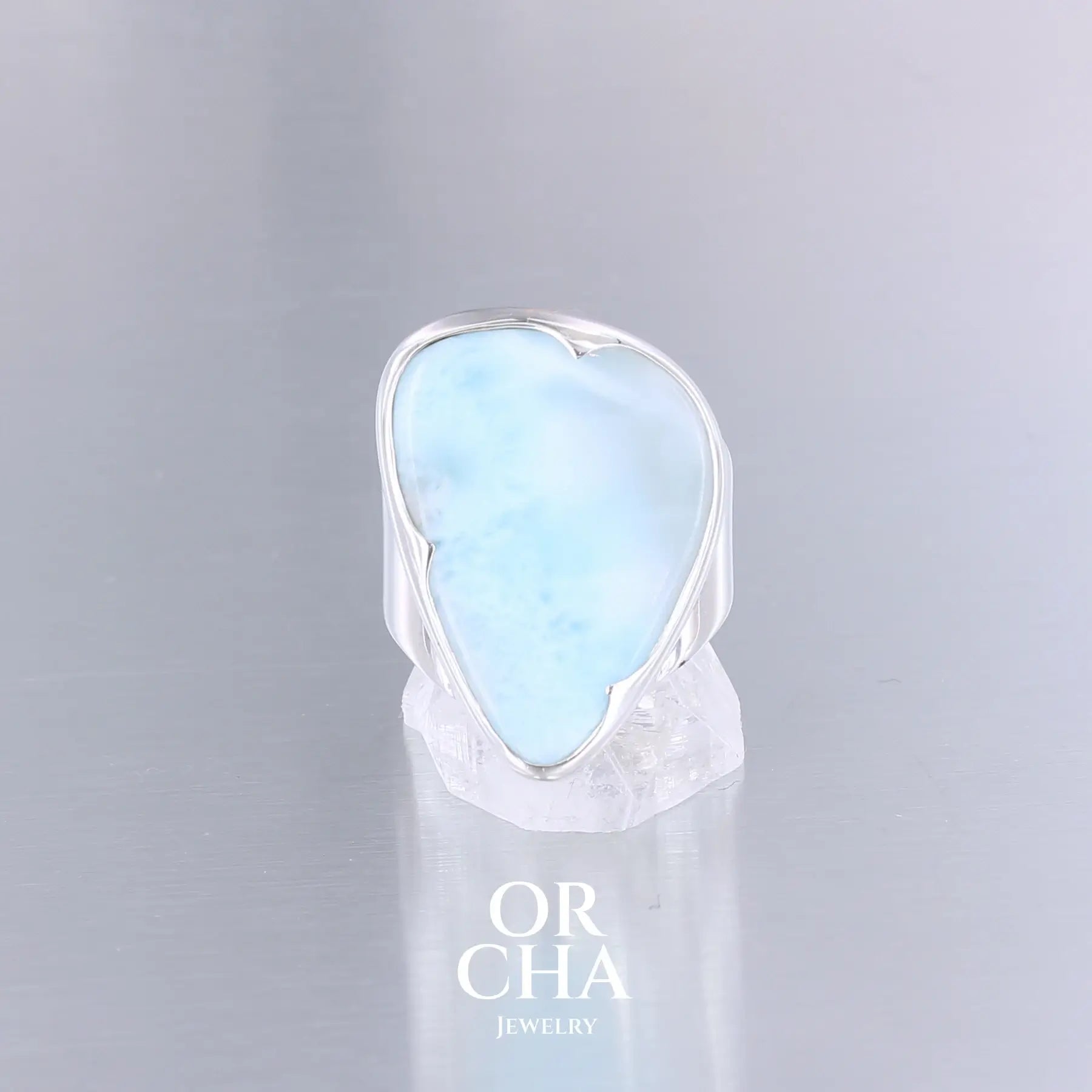 Bague de créateur pour femme en argent massif sertie d'un Larimar de République dominicaine. Cabochon de forme fantaisie, pierre naturelle de couleur bleu clair présentant de légère marbrures blanches. Qualité translucide. Taille 54. Bijoux unique, éthique et durable présenté dans un coffret de notre marque, prêt à offrir. Livraison offerte, certificat d'authenticité, service client.
