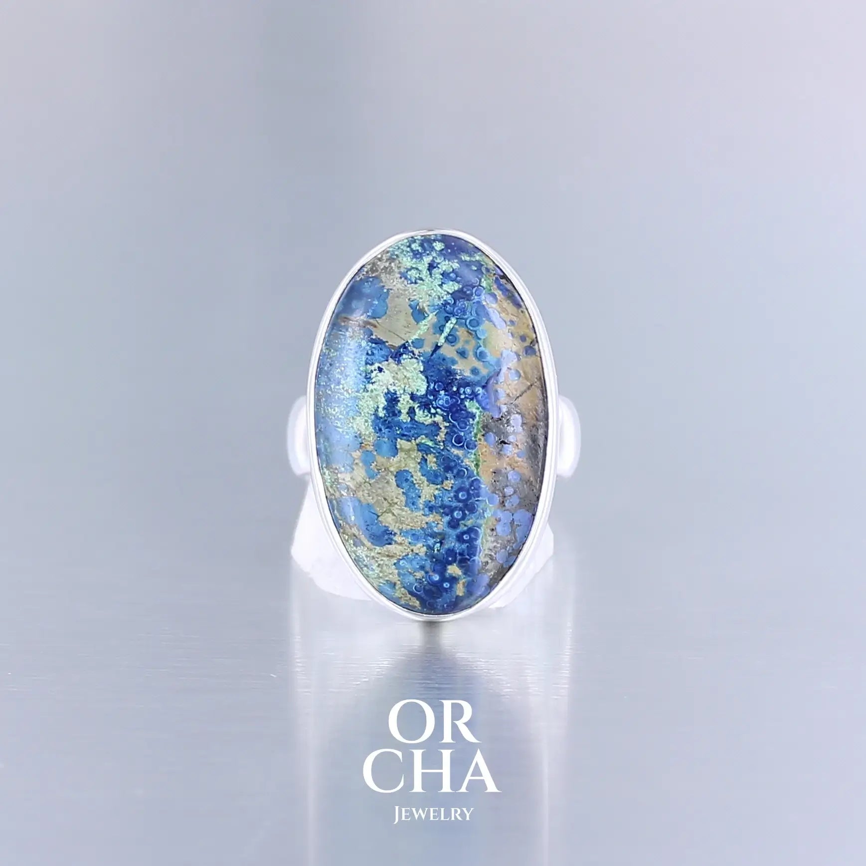 Bague pour femme en argent sterling 925 ornée d’une Azurite, pierre naturelle de couleur bleue. Cette bague est une pièce unique, en taille 60. Sa pierre naturelle azurite ovale d'un bleu profond, veinée de malachite verte évoque les ciels d'orage et les océans primaires.  Le serti clos épouse parfaitement la forme naturelle de la pierre. Bijoux unique, éthique et durable présenté dans un coffret de notre marque, prêt à offrir. Livraison offerte, certificat d'authenticité, service client.