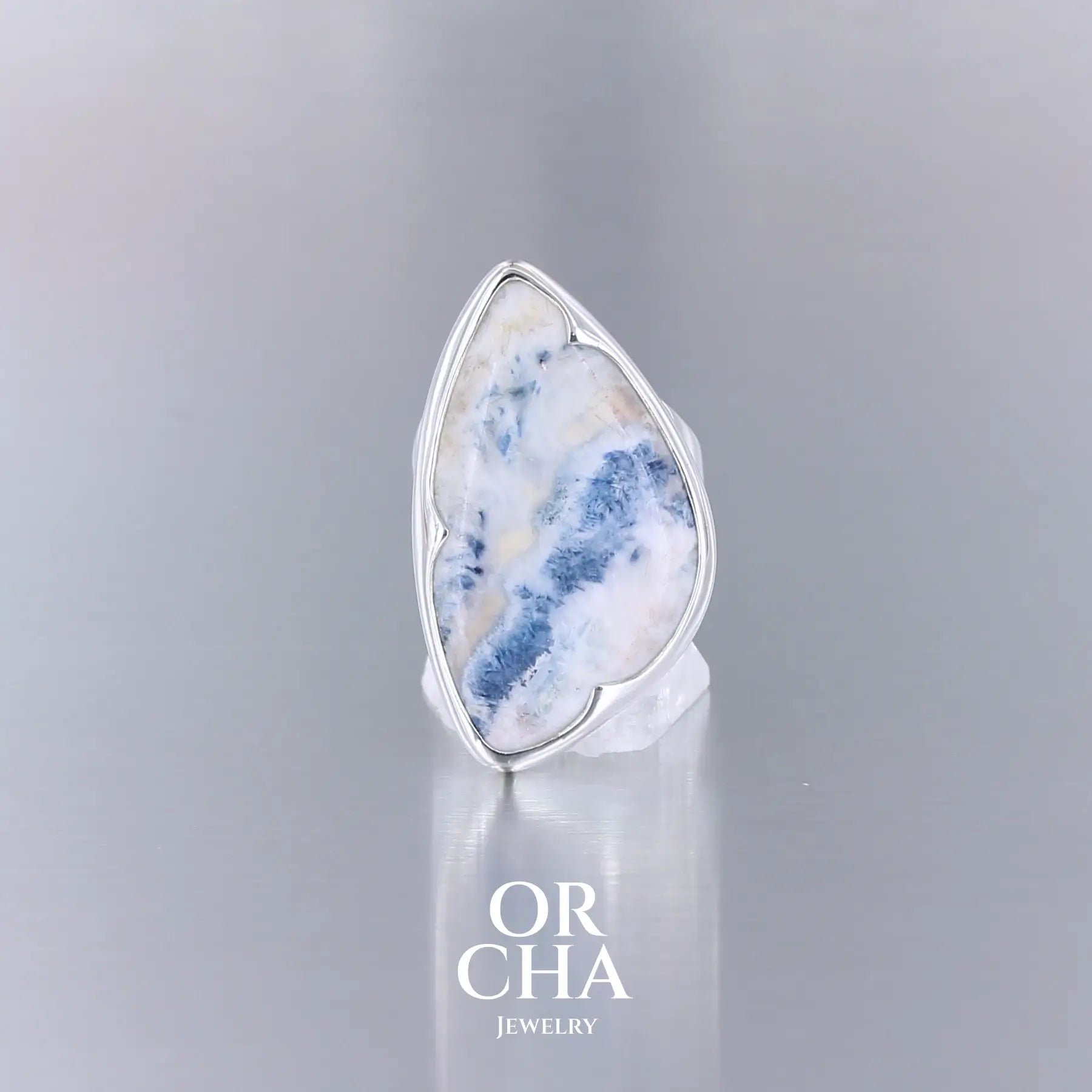 Bague de créateur pour femme en argent massif sertie d'une scheelite bleue. Pierre naturelle de couleur bleu, beige creme et blanc de qualité  opaque. Taille 58. Bijoux unique, éthique et durable présenté dans un coffret de notre marque, prêt à offrir. Livraison offerte, certificat d'authenticité, service client.