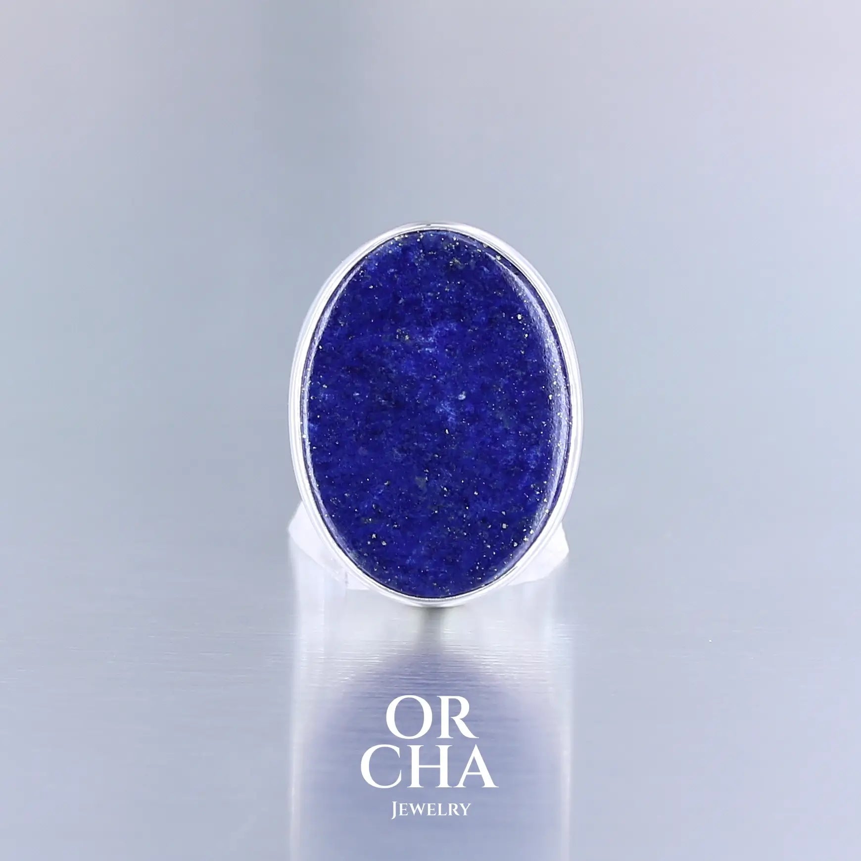 Bague pour femme en argent sterling 925 ornée d’un Lapis Lazuli de forme ovale, pierre naturelle de couleur bleue et inclusion dorées de pyrite. Cette bague artisanale est une pièce unique, en taille 54.  Le serti clos épouse parfaitement la forme naturelle de la pierre. Bijoux unique, éthique et durable présenté dans un coffret de notre marque, prêt à offrir. Livraison offerte, certificat d'authenticité, service client.