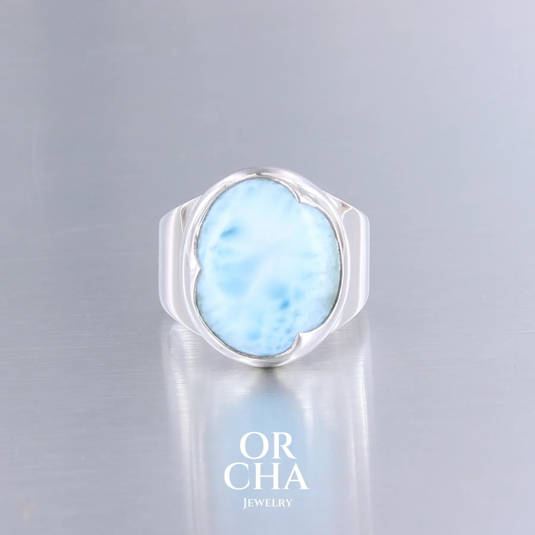 Bague artisanale en argent sterling 925 sertie d'une pierre naturelle de larimar bleu intense de République Dominicaine. La gemme ovale présente des nuances bleu caraïbe profondes avec des veines blanches nacrées rappelant les vagues océaniques. Sertissage clos  en argent massif épousant parfaitement les contours naturels de la pierre. Bague  Taille 54. Bijoux unique, éthique et durable présenté dans un coffret de notre marque, prêt à offrir. Livraison offerte, certificat d'authenticité, service client.