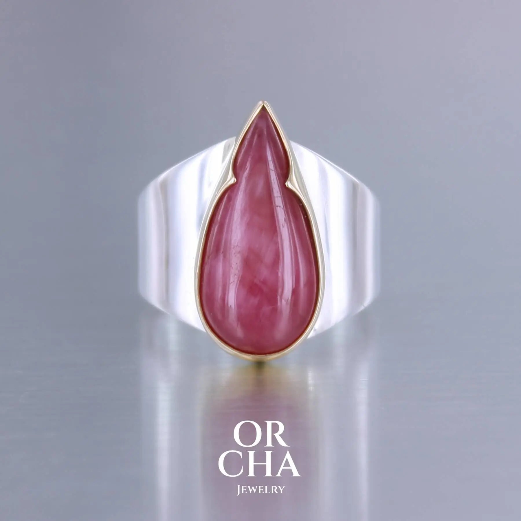 Grande bague pour femme en or 18k et argent massif sertie d'une Rhodonite. Pierre cabochon en forme de goutte, pierre naturelle de qualité rare de couleur rouge coquelicot. Pierre fine de qualité  opaque. Taille 56. Bijoux unique, éthique et durable présenté dans un coffret de notre marque, prêt à offrir. Livraison offerte, certificat d'authenticité, service client.
