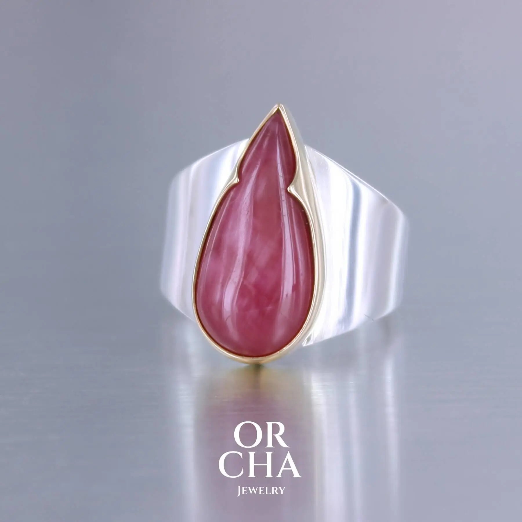 Grande bague pour femme en or 18k et argent massif sertie d'une Rhodonite. Pierre cabochon en forme de goutte, pierre naturelle de qualité rare de couleur rouge coquelicot. Pierre fine de qualité  opaque. Taille 56. Bijoux unique, éthique et durable présenté dans un coffret de notre marque, prêt à offrir. Livraison offerte, certificat d'authenticité, service client.