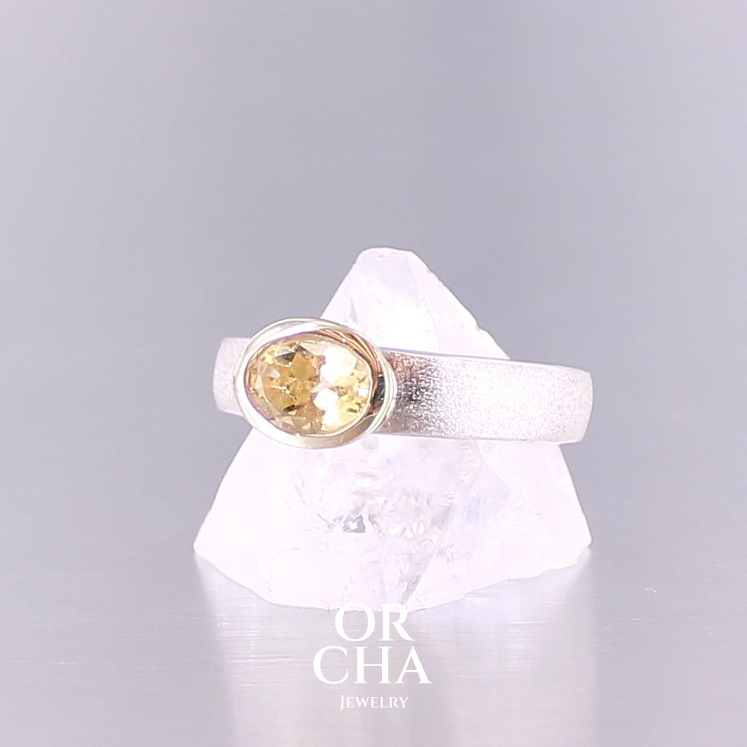 Bague anneau pour femme en argent massif et or sertie d'une Citrine. Pierre facettée de forme ovale, de qualité transparente, propre à l'oeil. Pierre naturelle de couleur jaune doré lumineux. Bijoux unique, éthique et durable présenté dans un coffret de notre marque, prêt à offrir. Livraison offerte, certificat d'authenticité, service client.