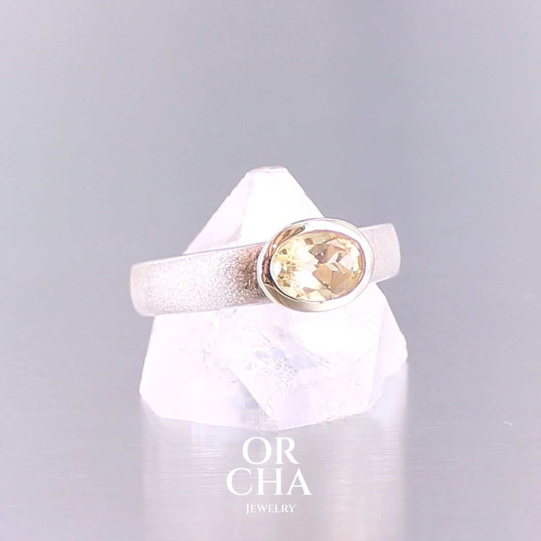 Bague anneau pour femme en argent massif et or sertie d'une Citrine. Pierre facettée de forme ovale, de qualité transparente, propre à l'oeil. Pierre naturelle de couleur jaune doré lumineux. Bijoux unique, éthique et durable présenté dans un coffret de notre marque, prêt à offrir. Livraison offerte, certificat d'authenticité, service client.