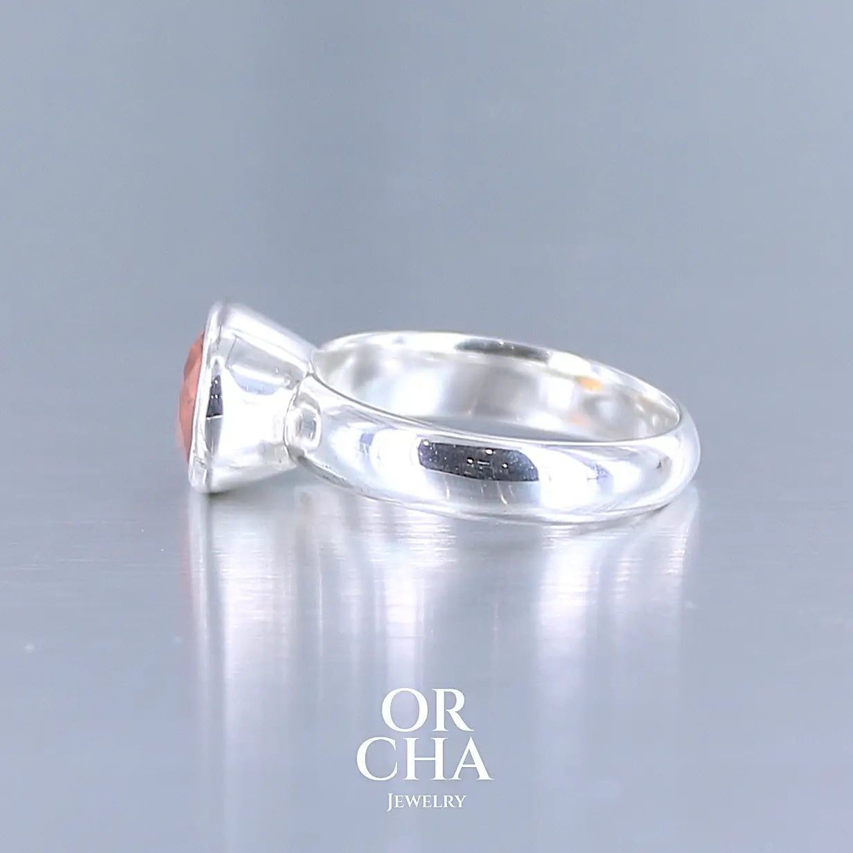 Profil d'une bague cocktail pour femme en argent massif sertie d'un Grenat Spessartite. Pierre facettée de forme ovale de qualité transparente, propre à l'oeil. Pierre naturelle de couleur orange intense, ce Grenat est également appelé Grenat "Fanta" en rapport à la couleur saturé du célèbre soda. Tailles 58.5.  Bijoux unique, éthique et durable présenté dans un coffret de notre marque, prêt à offrir. Livraison offerte, certificat d'authenticité, service client.