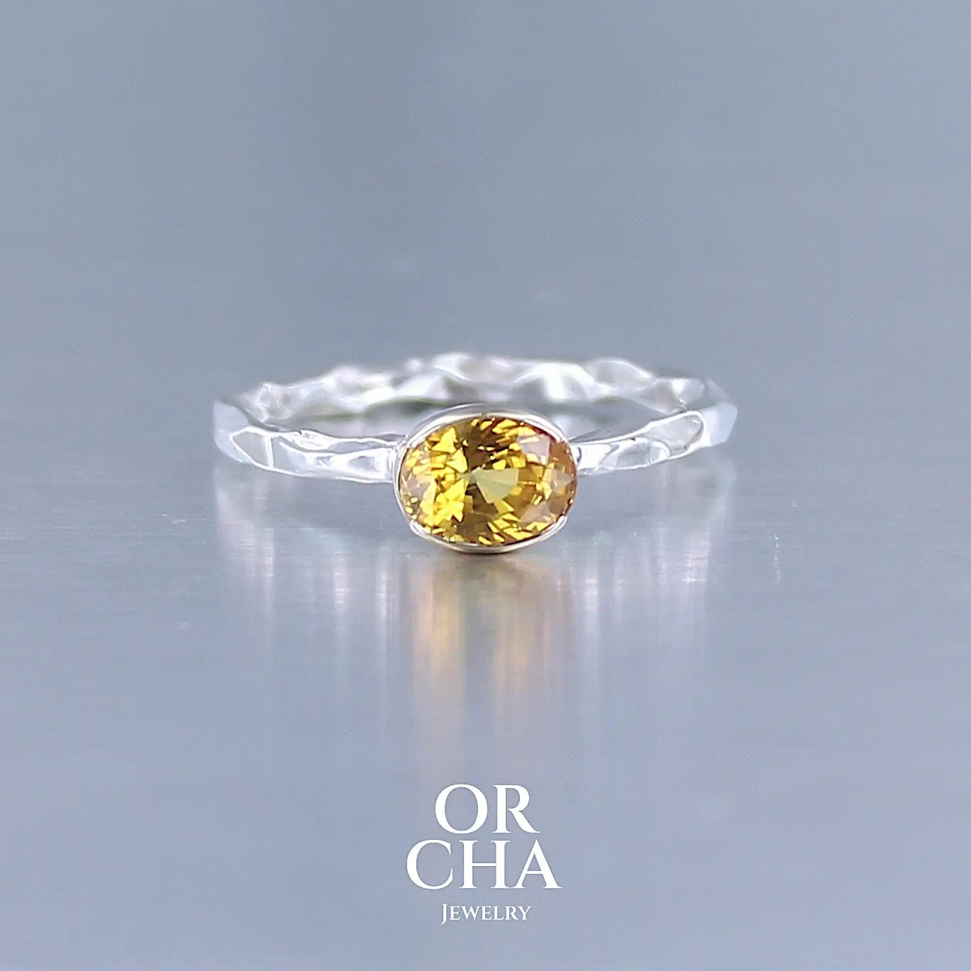 Bague anneau pour femme en argent massif et or 12 k sertie d'un Saphir jaune orangé très lumineux. Pierre facettée de forme ovale, de qualité transparente, propre à l'oeil. Pierre chauffée et traitée au beryllium. Bijoux unique, éthique et durable présenté dans un coffret de notre marque, prêt à offrir. Livraison offerte, certificat d'authenticité, service client.
