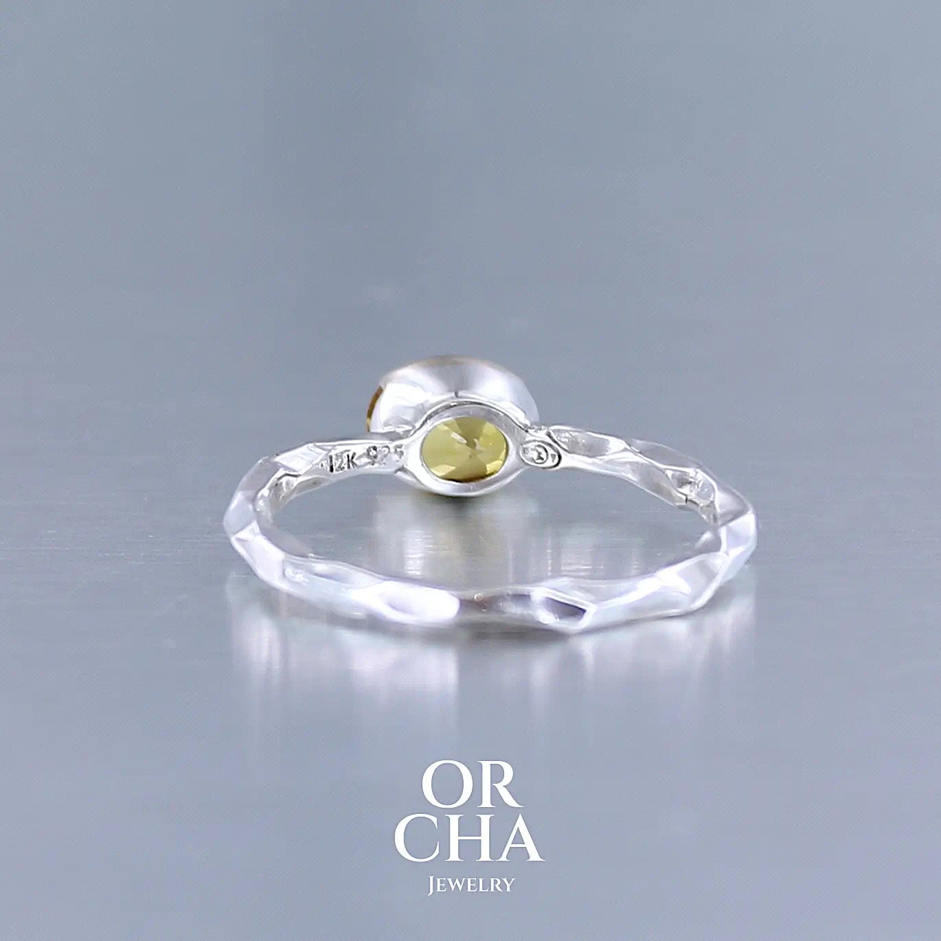 vue arrière d'une bague anneau pour femme en argent massif et or 12 k sertie d'un Saphir jaune orangé très lumineux. Pierre facettée de forme ovale, de qualité transparente, propre à l'oeil. Pierre chauffée et traitée au beryllium. Bijoux unique, éthique et durable présenté dans un coffret de notre marque, prêt à offrir. Livraison offerte, certificat d'authenticité, service client.