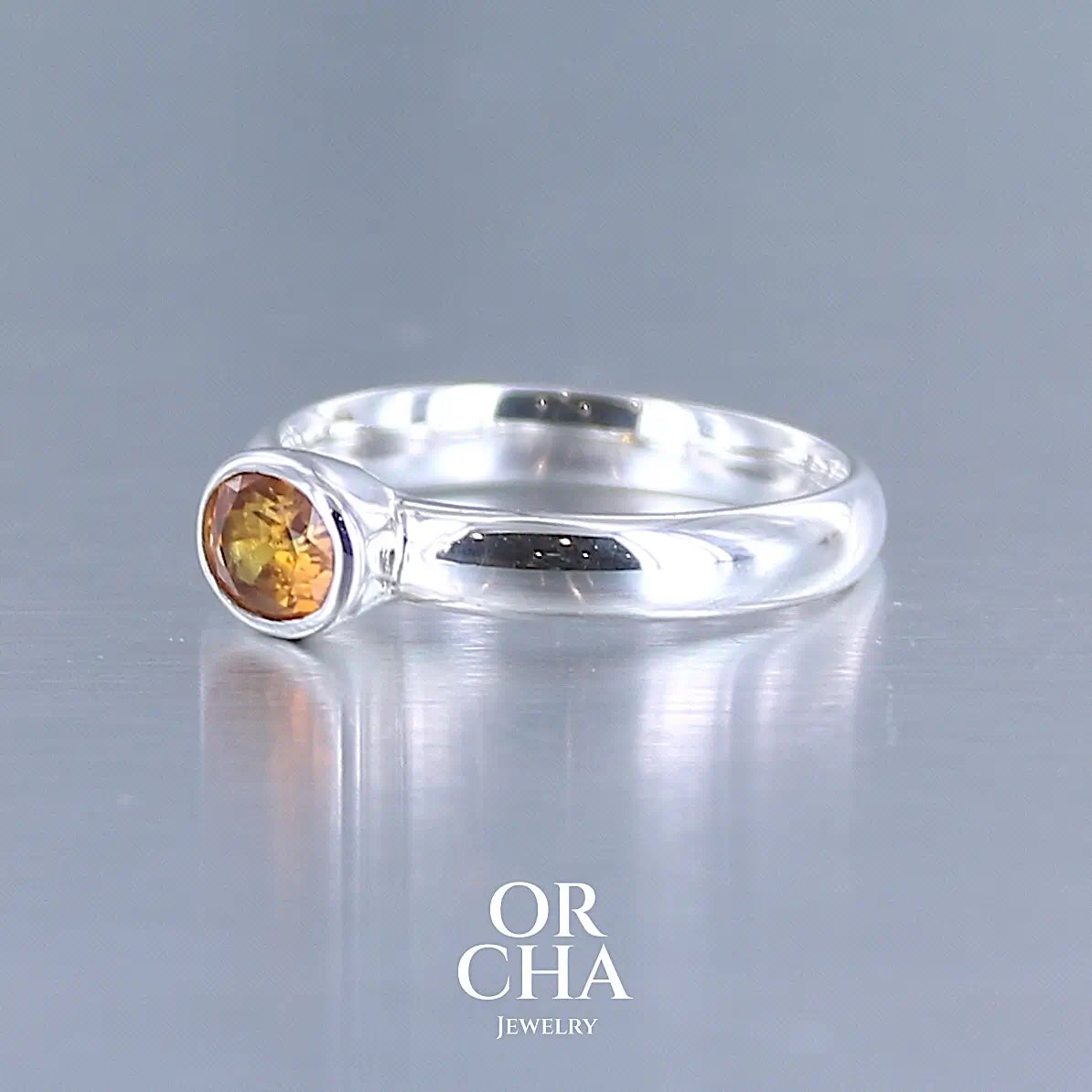 photo de profil d'une bague anneau en argent massif sertie d'un Saphir orange. Pierre facettée de forme ovale de qualité transparente, propre à l'oeil. Pierre chauffe et traité au beryllium de couleur orange intense. Tailles 56. Pour homme et femme. Bijoux unique, éthique et durable présenté dans un coffret de notre marque, prêt à offrir. Livraison offerte, certificat d'authenticité, service client.