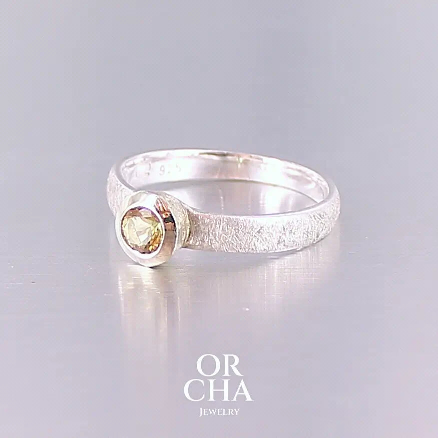 Profil d'une bague anneau pour femme en argent massif et or sertie d'une Héliodore. Pierre facettée de forme ronde, de qualité transparente, propre à l'oeil. Pierre naturelle de couleur jaune doré lumineux. Bijoux unique, éthique et durable présenté dans un coffret de notre marque, prêt à offrir. Livraison offerte, certificat d'authenticité, service client.