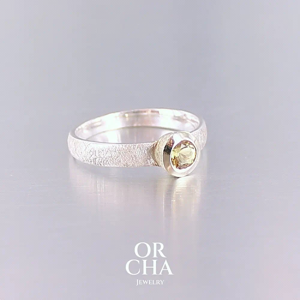 Profil d'une bague anneau pour femme en argent massif et or sertie d'une Héliodore. Pierre facettée de forme ronde, de qualité transparente, propre à l'oeil. Pierre naturelle de couleur jaune doré lumineux. Bijoux unique, éthique et durable présenté dans un coffret de notre marque, prêt à offrir. Livraison offerte, certificat d'authenticité, service client.