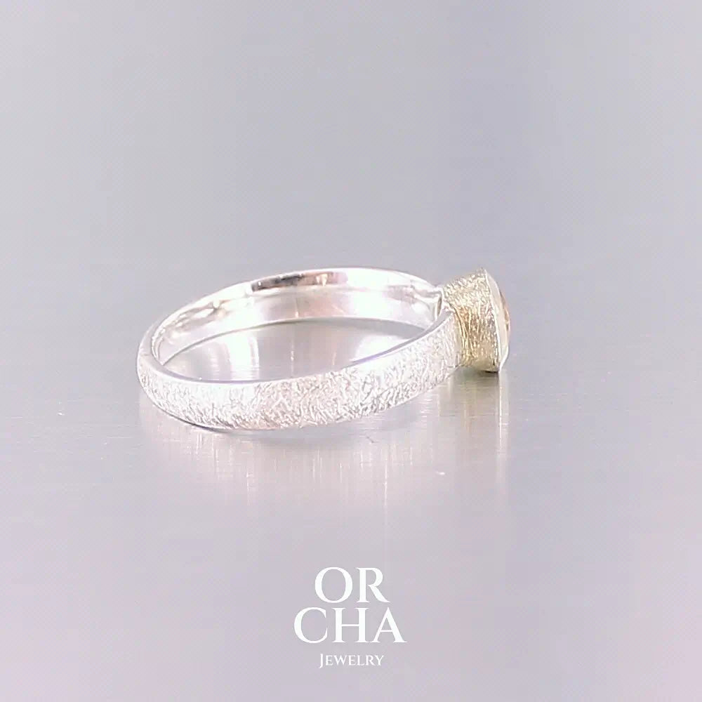 Profil d'une bague anneau pour femme en argent massif et or sertie d'une Héliodore. Pierre facettée de forme ronde, de qualité transparente, propre à l'oeil. Pierre naturelle de couleur jaune doré lumineux. Bijoux unique, éthique et durable présenté dans un coffret de notre marque, prêt à offrir. Livraison offerte, certificat d'authenticité, service client.