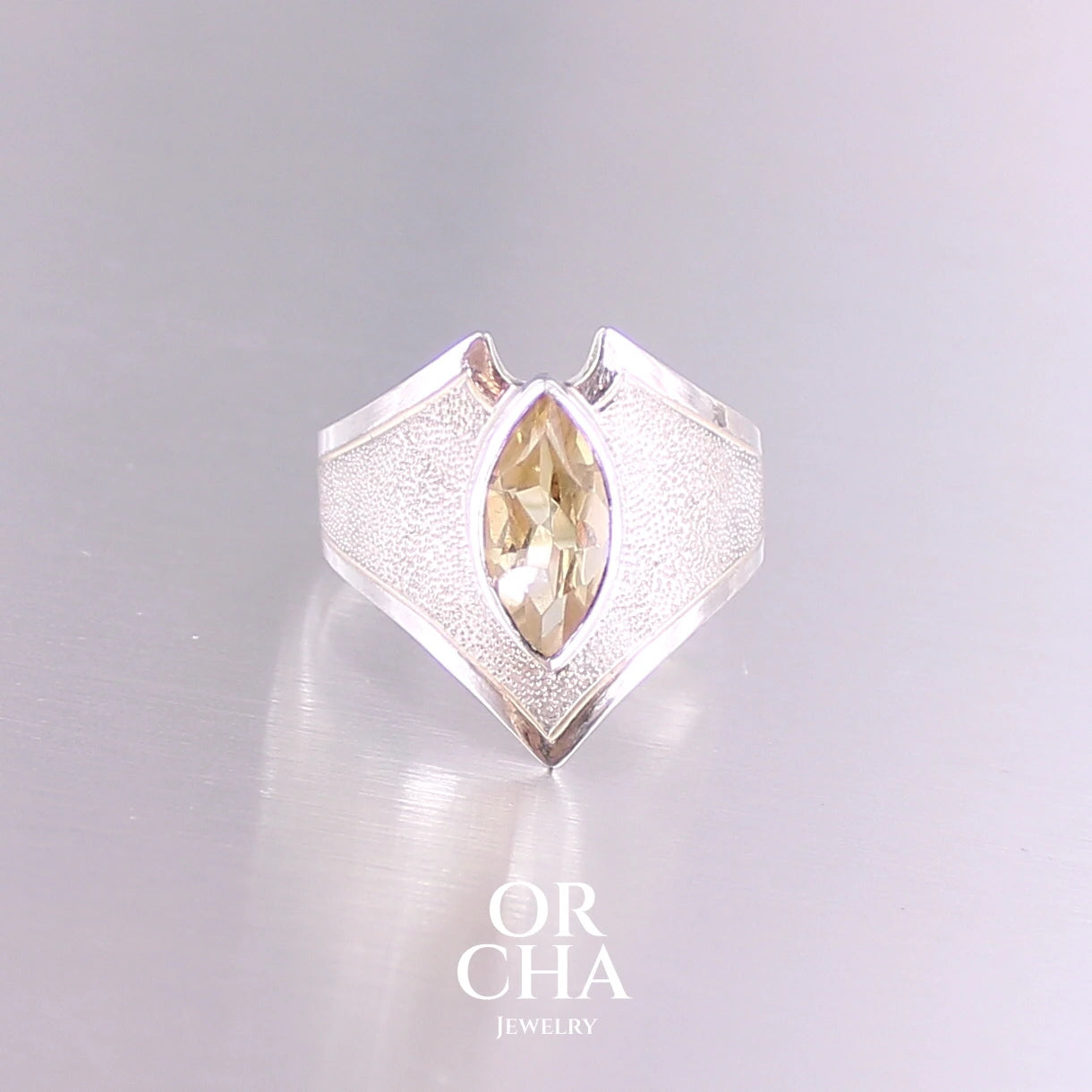 Bague contemporaine en forme pour femme en argent massif sertie d'une Citrine. Pierre facettée en forme de marquise de qualité transparente, propre à l'oeil. Pierre naturelle de couleur jaune doré lumineux. Bijoux unique, éthique et durable présenté dans un coffret de notre marque, prêt à offrir. Livraison offerte, certificat d'authenticité, service client.

